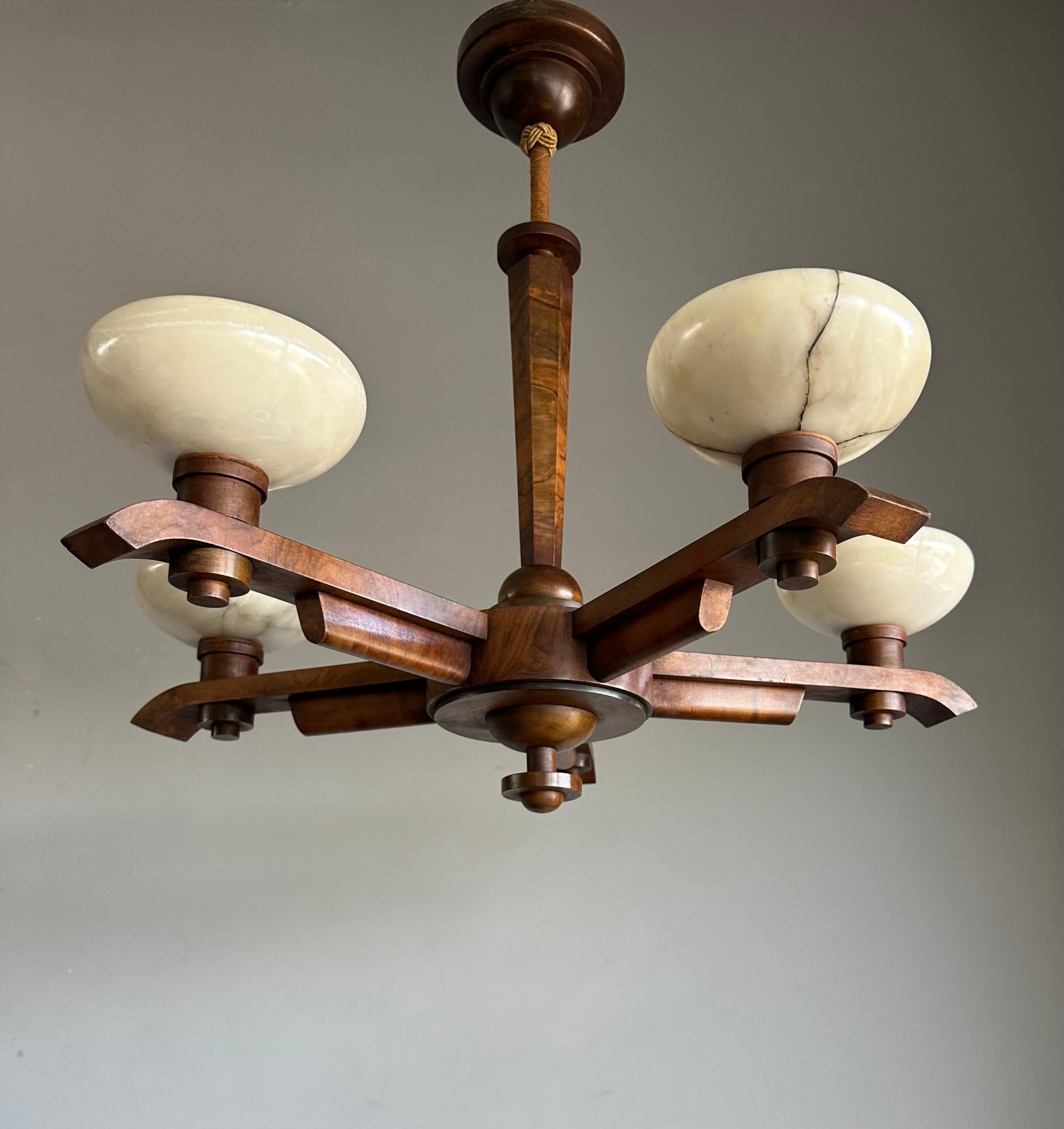 This also unique and good size, eye pleasing Art Deco chandelier, stands out for several reasons:

Firstly, it has a stunning walnutwood 'body' which is in excellent condition. 
Secondly, its perfect Art Deco design makes it a true joy to own and to