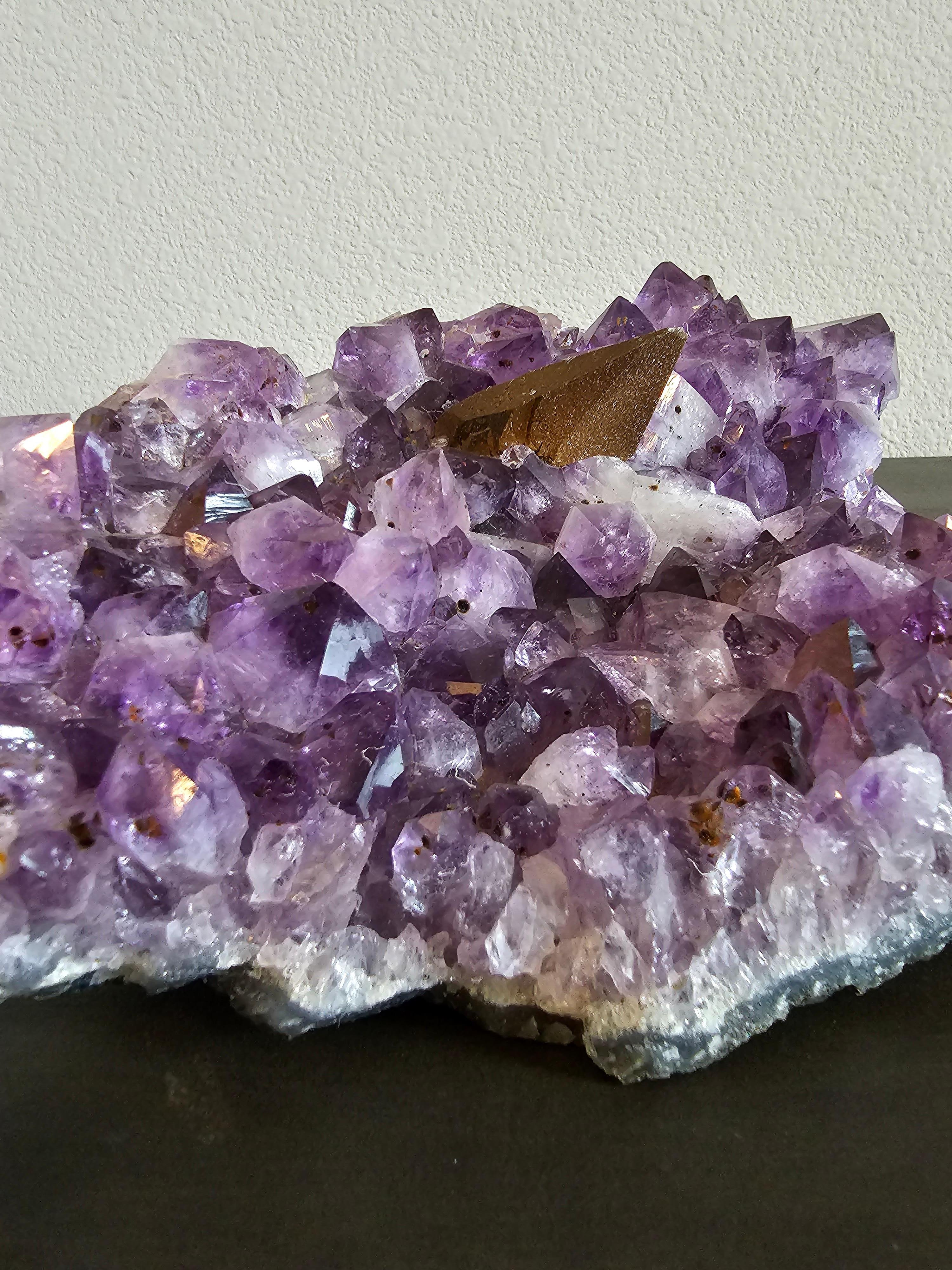 Un gran ejemplar brillante de amatista natural que muestra grandes terminaciones cristalinas, ricas inclusiones y formaciones de calcita por todas partes, y una única espiga grande de hematites.

Dimensiones: (aprox.)
11,5