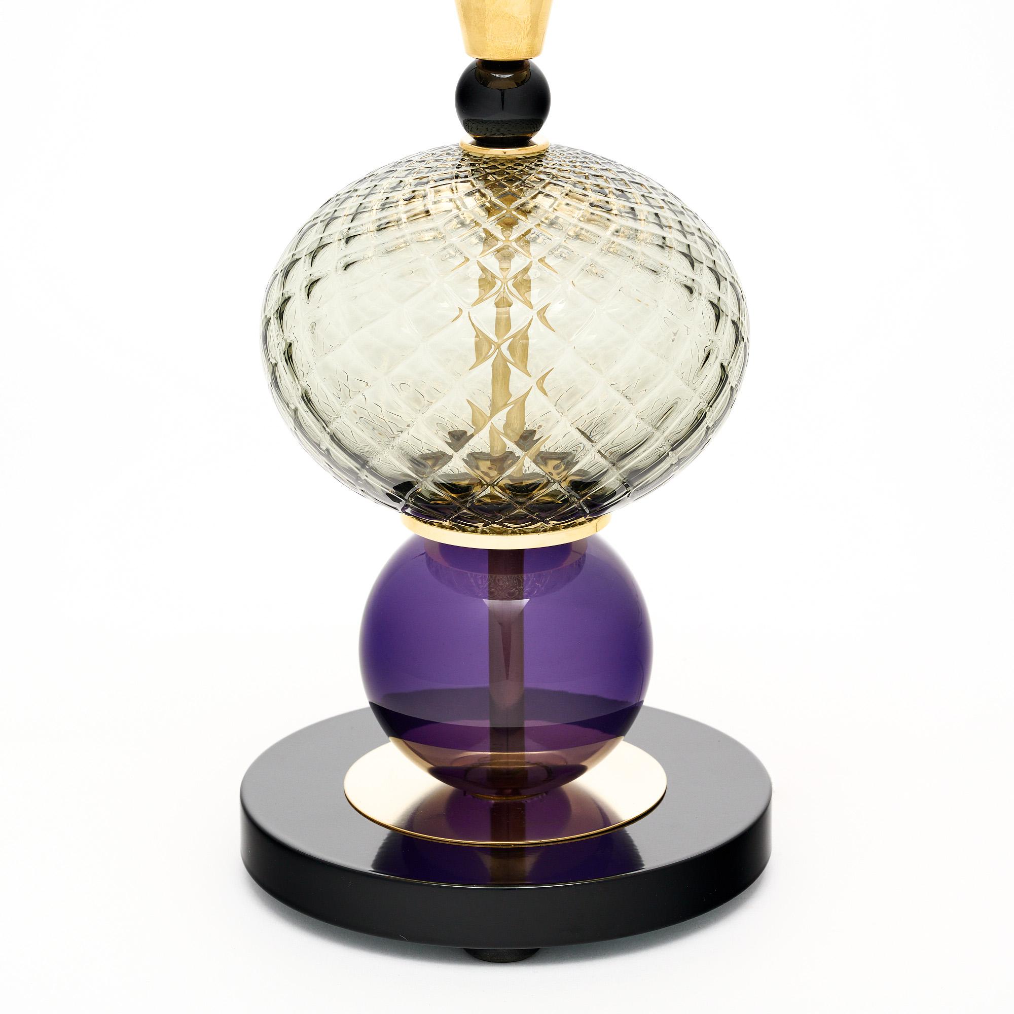 Pair of table lamps made of hand-blown glass elements from Murano, Italy outside of Venice. Each lamp features unique glass components in purple, black, and gold tones on a brass structure. We love the geometric forms and bold tones this pair brings