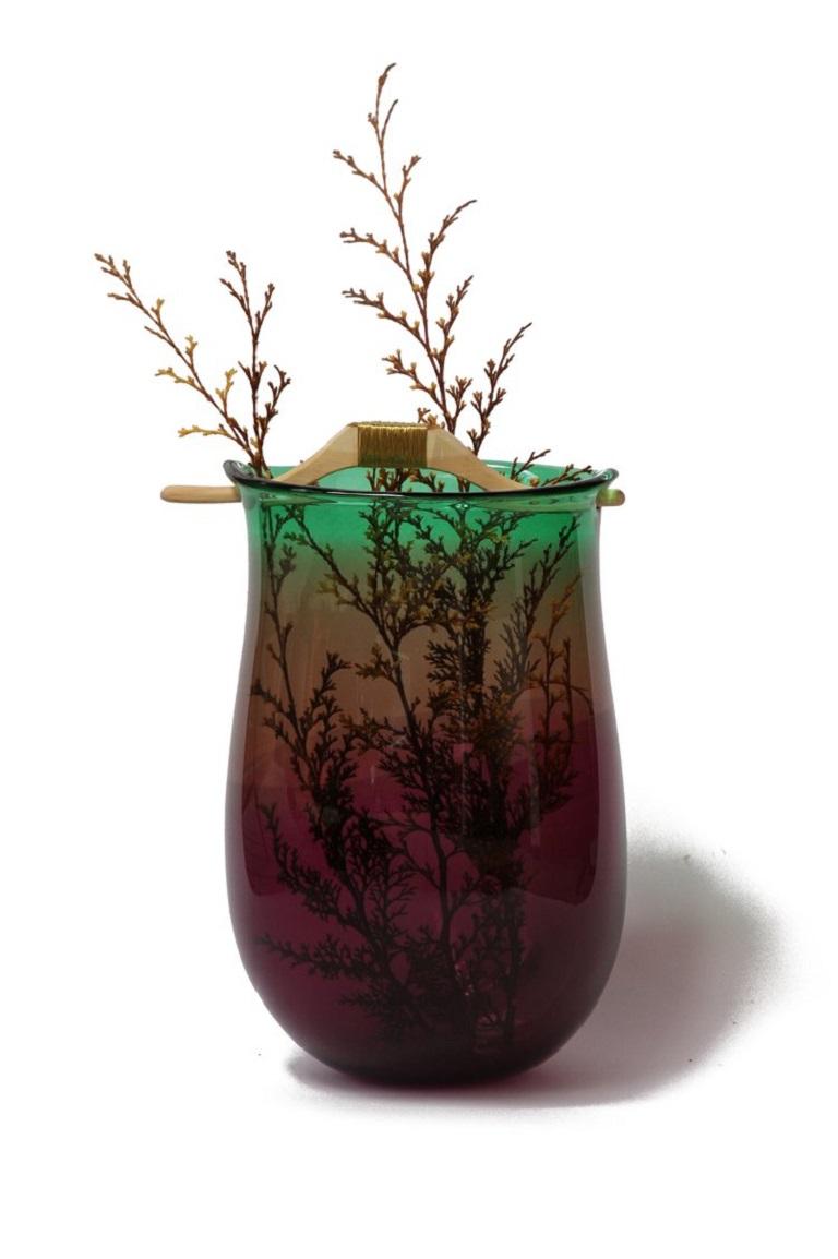 Purple and green Heiki vase II, Pia Wüstenberg
Dimensions: D 20-22 x H 32-40
Materials: glass, wood, metal wire
Available in other colors.

Inspired by a simple fix on an old sauna ladle handle, fixed with wire and outright everyday genius.