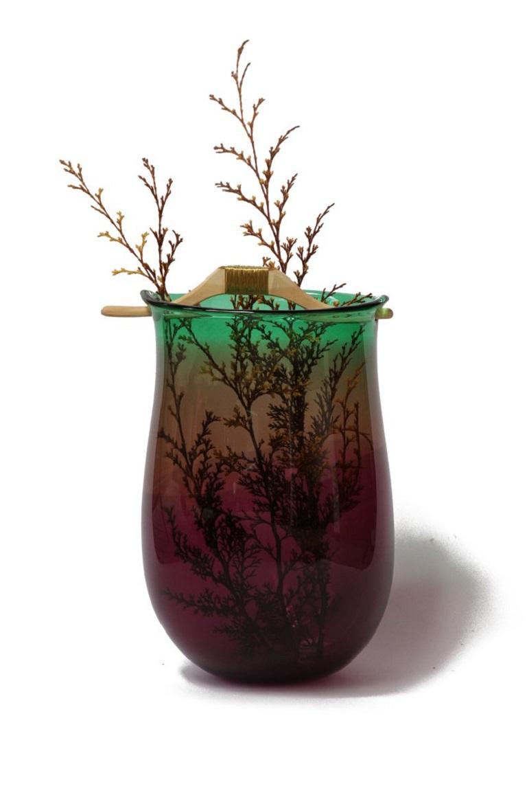 Vaso Heiki II viola e verde, Pia Wüstenberg
Dimensioni: D 20-22 x H 32-40
Materiali: vetro, Wood, filo di metallo
Disponibile in altri colori.

Ispirato da una semplice riparazione di un vecchio manico di una sauna, fissato con un filo di ferro