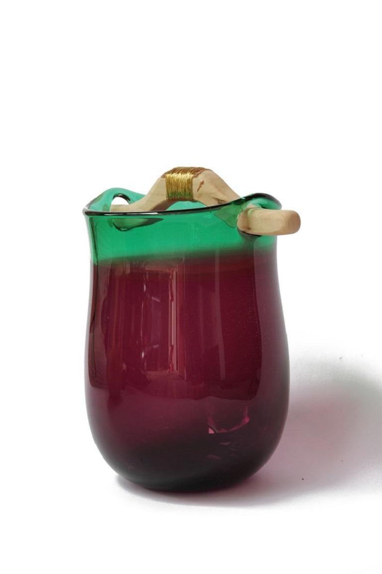 Purple and Green Heiki vase, Pia Wüstenberg
Dimensions: D 20-22 x H 32-40
Materials: glass, wood, metal wire
Available in other colors.

Inspired by a simple fix on an old sauna ladle handle, fixed with wire and outright everyday genius. Heiki