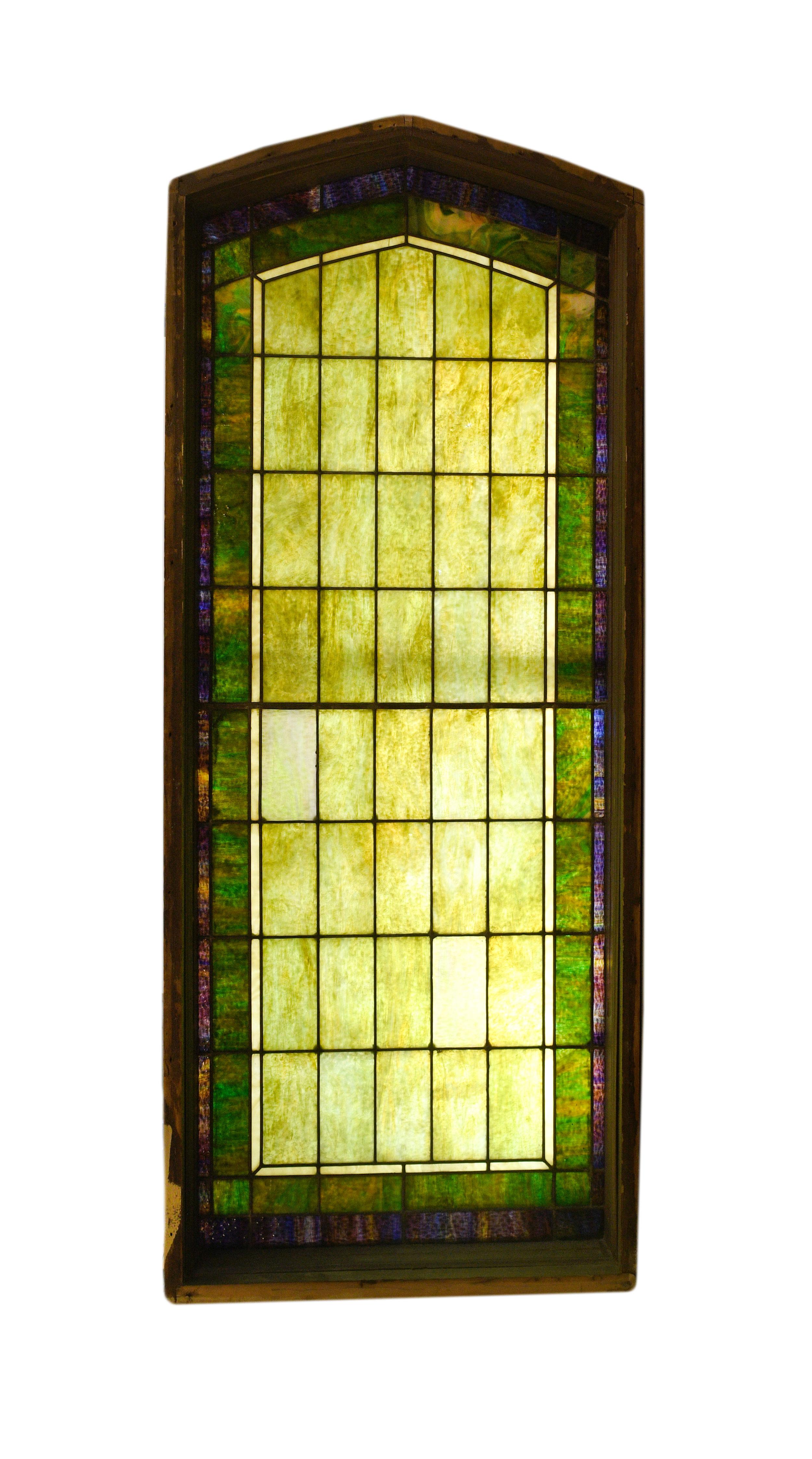 This large arched window is made of lovely purple and green slag glass and features a geometric design. When illuminated, the warmth of the colors on this window needs to be seen to believe!