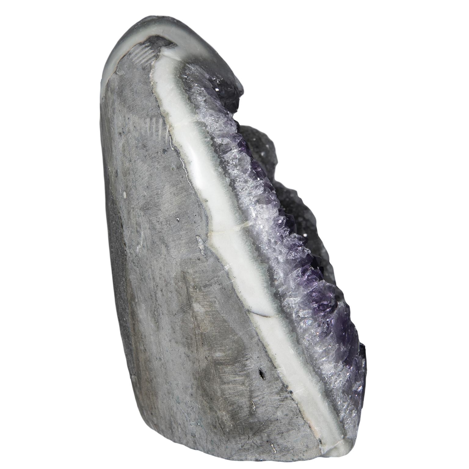 An exquisite and rare piece with a combination of 2 different formations on the same split geode. The piece displays purple amethyst crystals on one side and grey drusy quartz on the other. This freestanding decoratively sized piece presents a