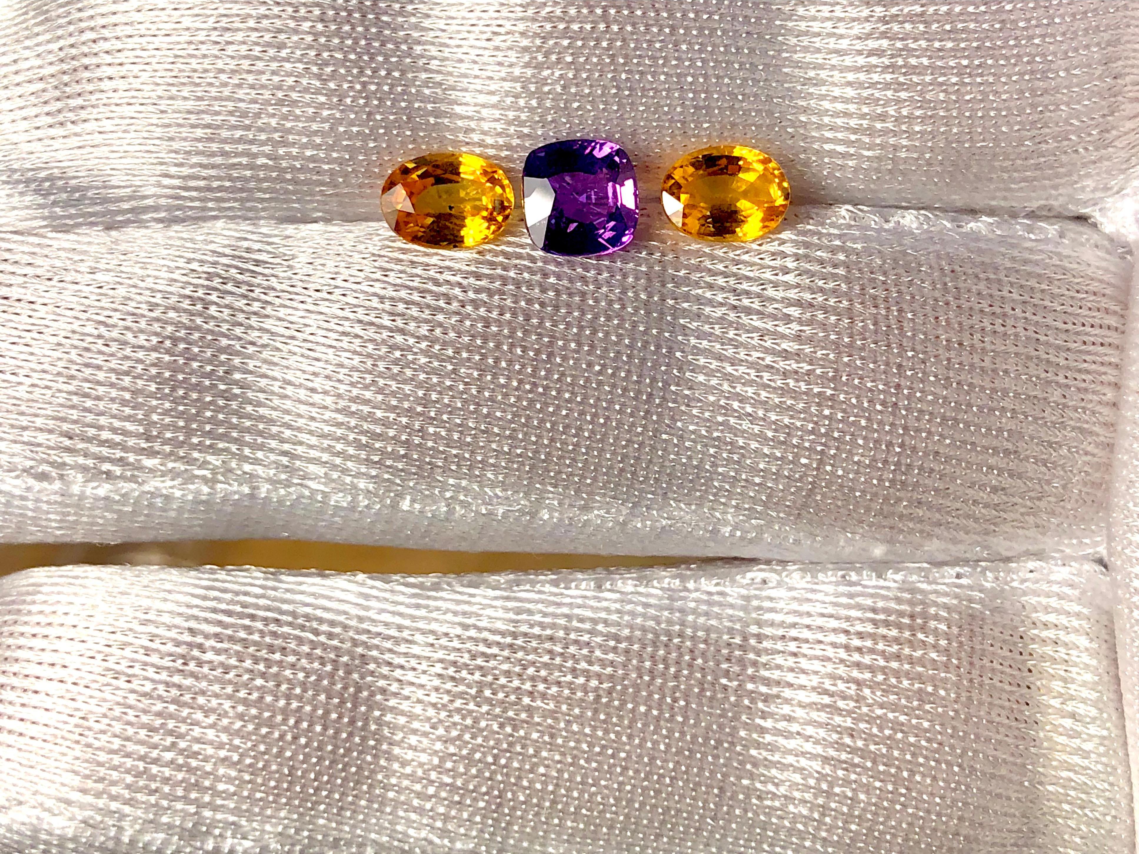 Three stone sapphires with a center high-quality cushion cut purple Ceylon sapphire 1.48 carats and two vibrant, yellow Ceylon oval cut sapphires weighing 2.18 carats.  
The trio of sapphires is of fine quality and clarity, with excellent cutting