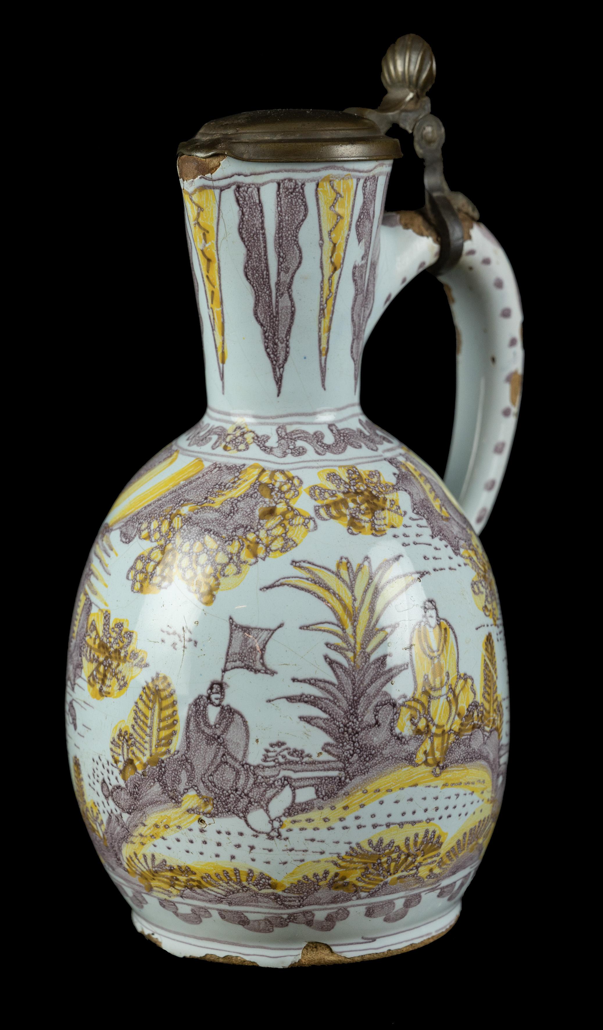 Purple and yellow chinoiserie wine jug. Delft, circa 1680
The ovoid wine jug stands on a low spreading foot, has a conical neck with spout and a pewter mount and cover. The ear-shaped handle has a rat tail finish. The jug is painted in purple and