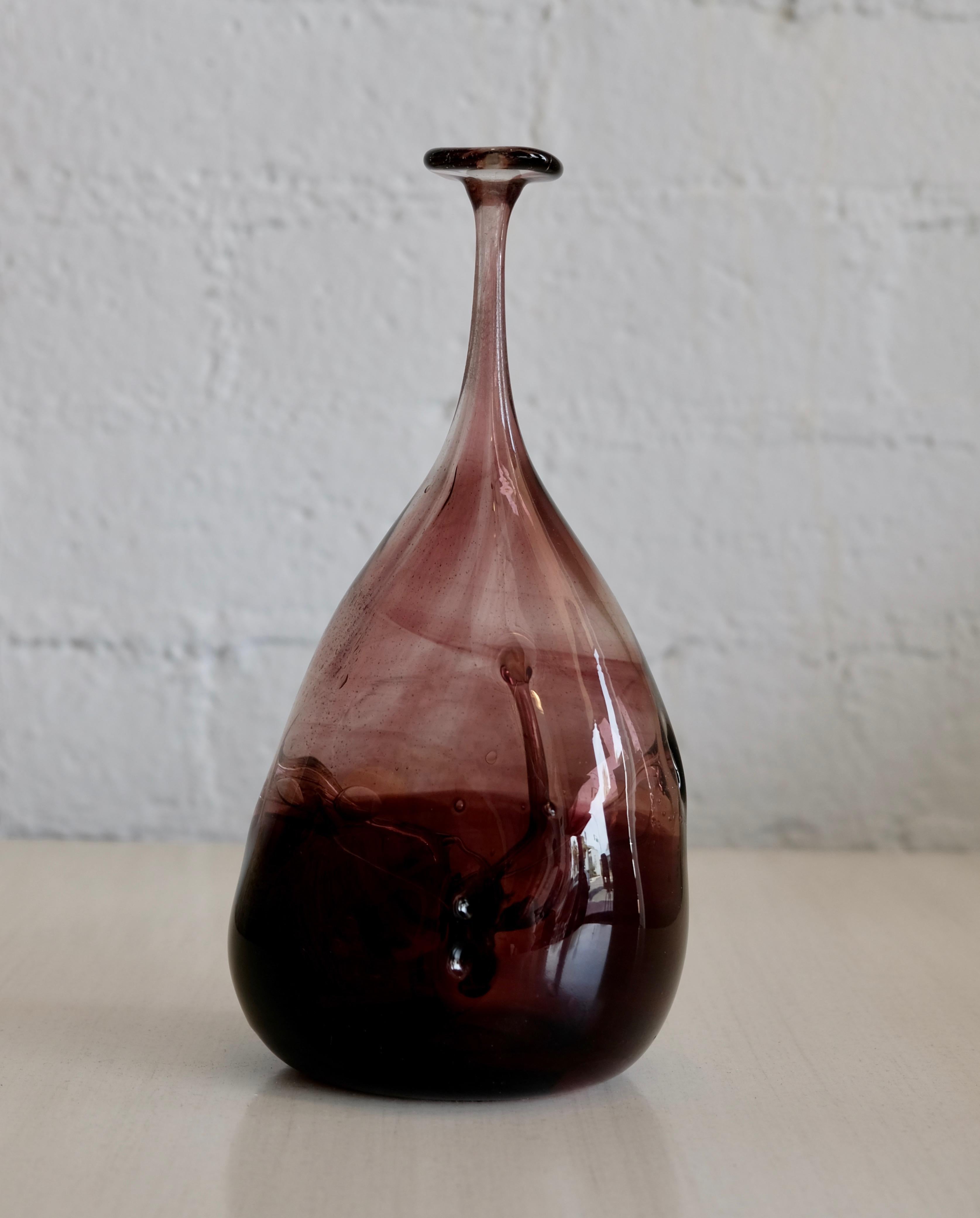 A hand blown art glass vase by Michael Robinson who was at the forefront of the Canadian Glass movement throughout the 1970s. This vase has pulled interior glass layers of that show off his delicate feathering technique. The purplish eggplant colors