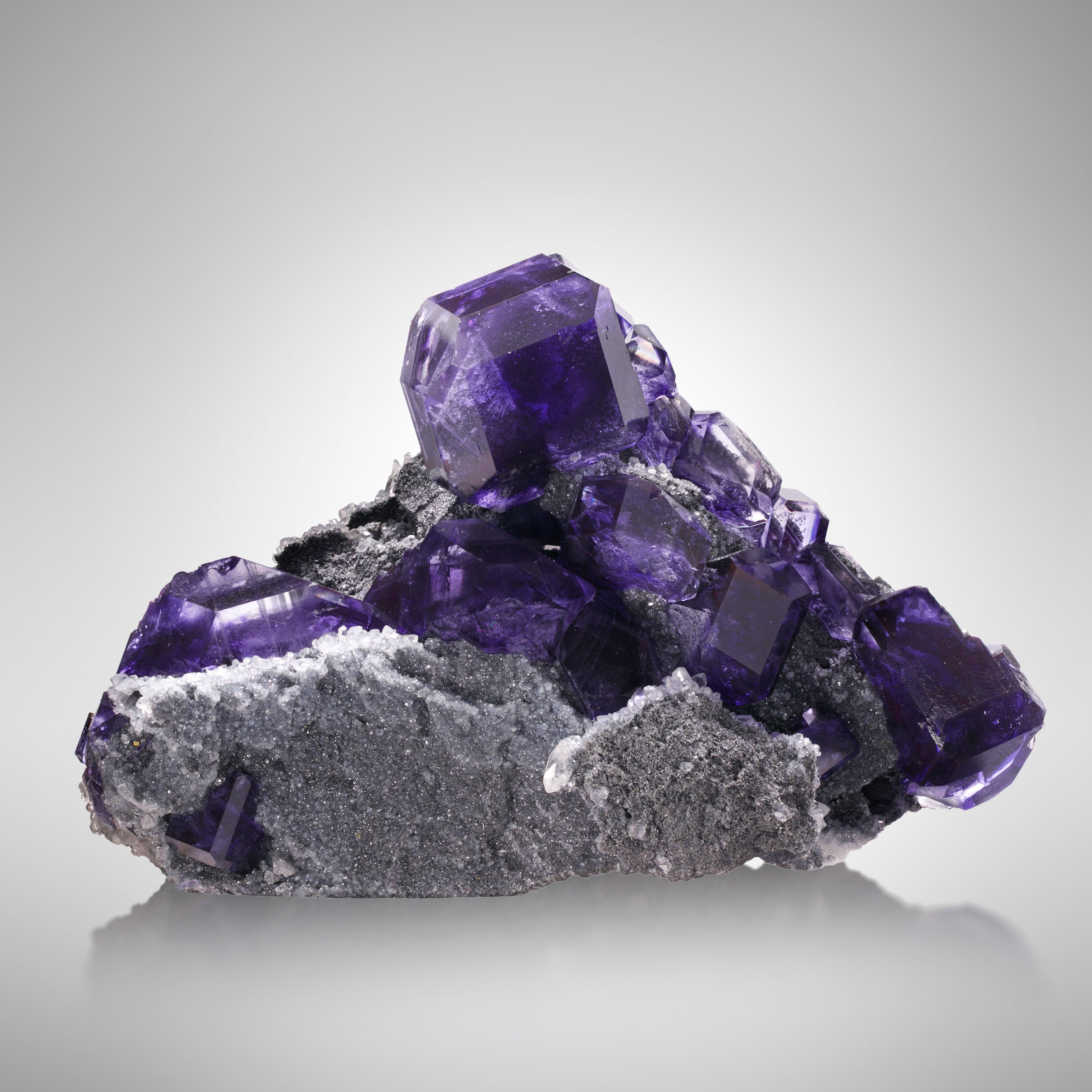 This breathtaking specimen comes from a distinctive group of fluorites that have affectionately been nicknamed, “tanzanite fluorite” for their gemlike aesthetics and color-shifting ability. Tanzanite fluorites appear blue in cool light and purple