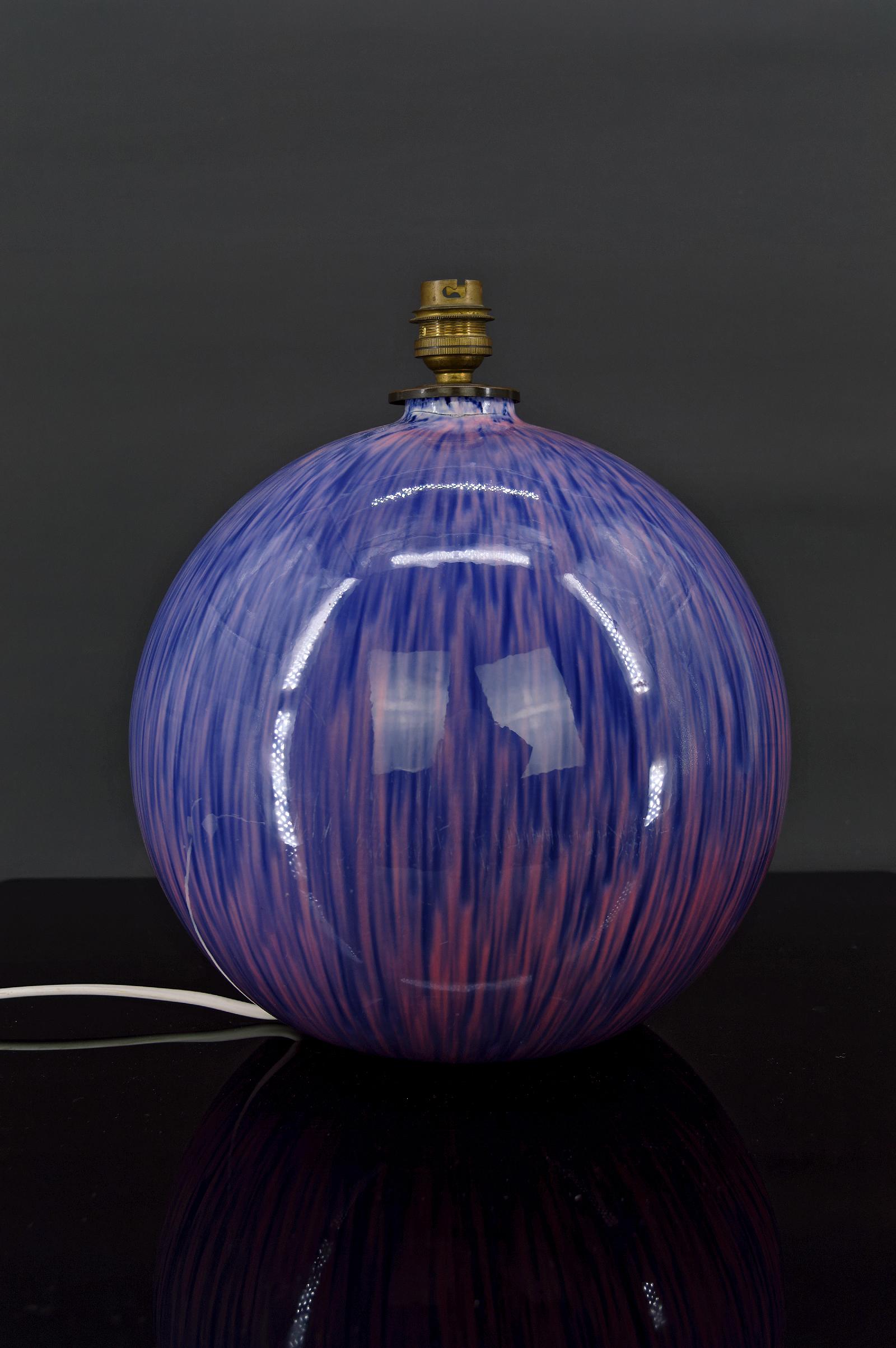 Beautiful round ball-shaped lamp. 
Ceramic in blue and purple tones.

Art Deco, Circa 1925.

Signed, numbered and logo ( locomotive coming out of a tunnel).
Artist and the country of origin are unknown

In good condition.

Dimensions:
Height 30