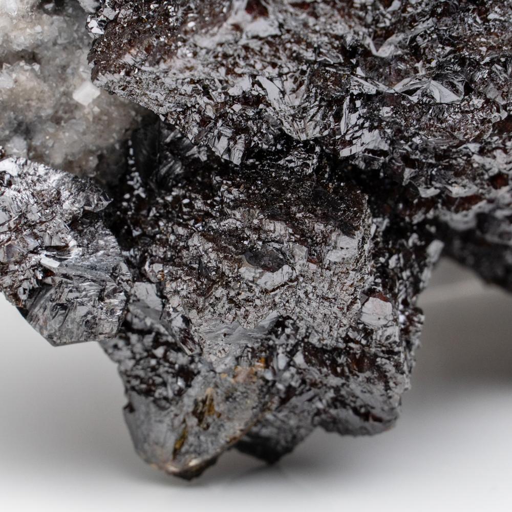 Cristal cúbico translúcido de fluorita púrpura superpuesto a un cristal de cuarzo transparente. Las superficies de fluorita se componen de pequeñas caras cristalinas paralelas acentuadas por pequeños grupos de microcristales de barita. Este