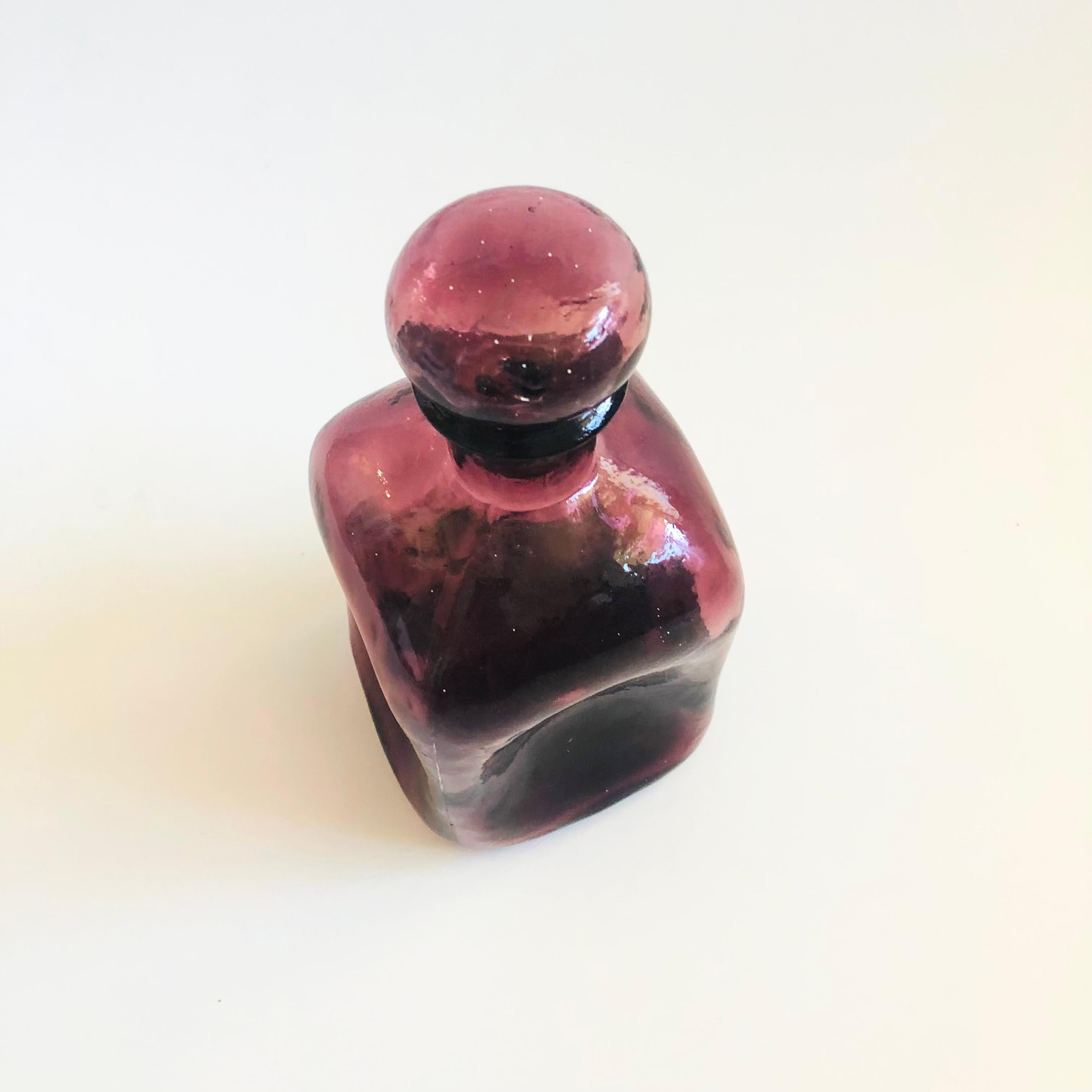 A vintage glass decanter. Beautiful dark purple color to the glass with round cork line stopper. Made a blown glass into a square shape with beautiful dimpling to the sides.

