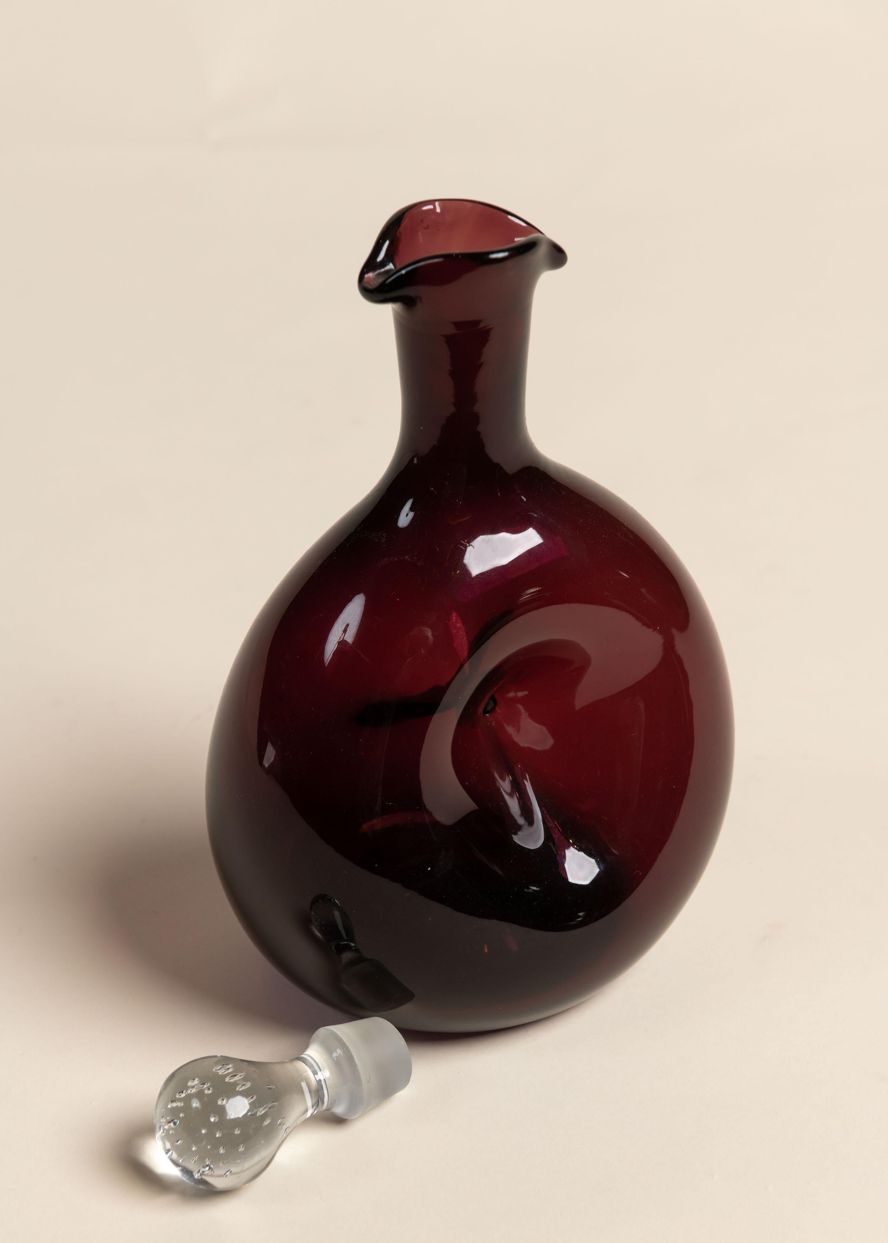 Swirling, purple class decanter with a round base and tapered neck with clear stopper. The perfect pop of color for any bar, alone or in a grouping. 
