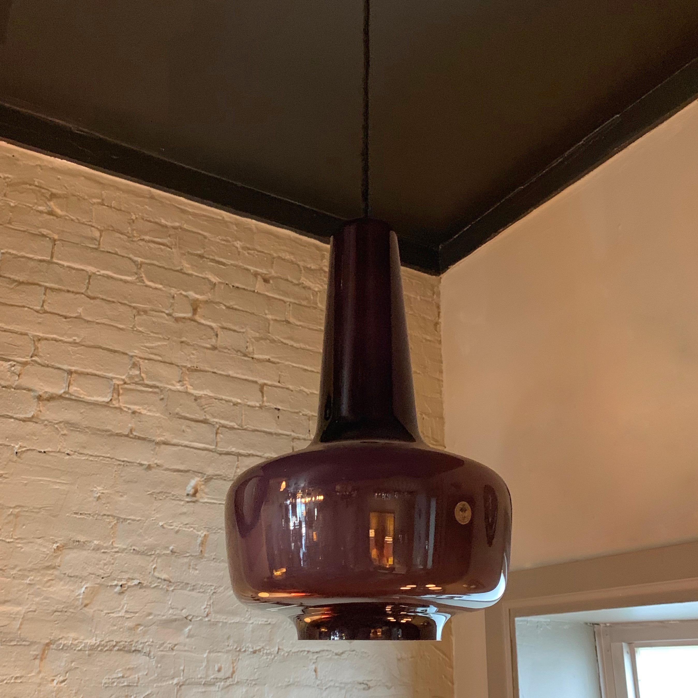 Danish modern, pendant light by Michael Bang for Holmegaard features a purple glass exterior and white glass interior that casts an opaque glow when lit.