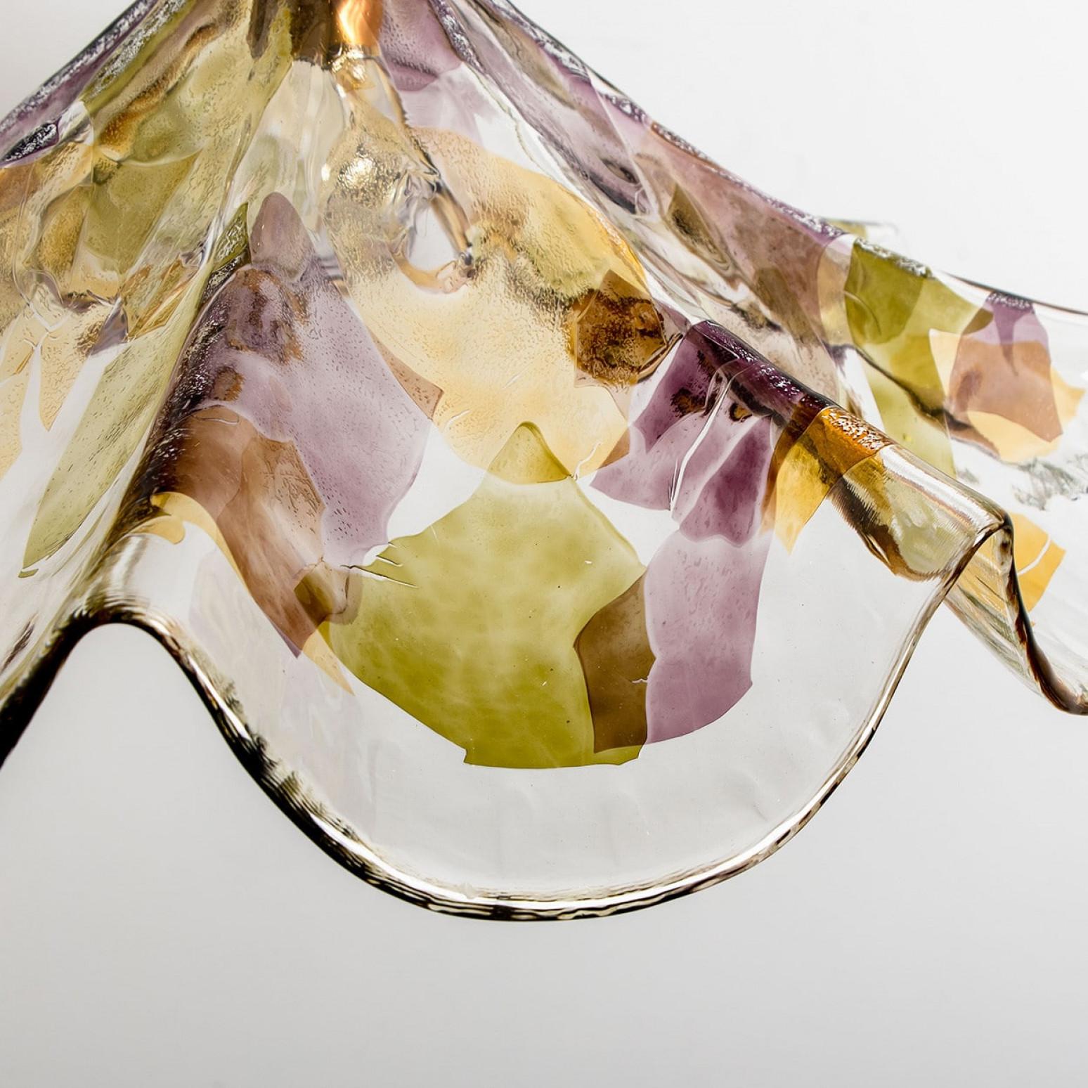 A colorful hand blown pendant of Murano glass. Made in Murano, Italy around 1980.
The glass is original hand blown murano glass in the colors purple, green and yellow. finished with a brass detail in top. A real eyecatcher in your