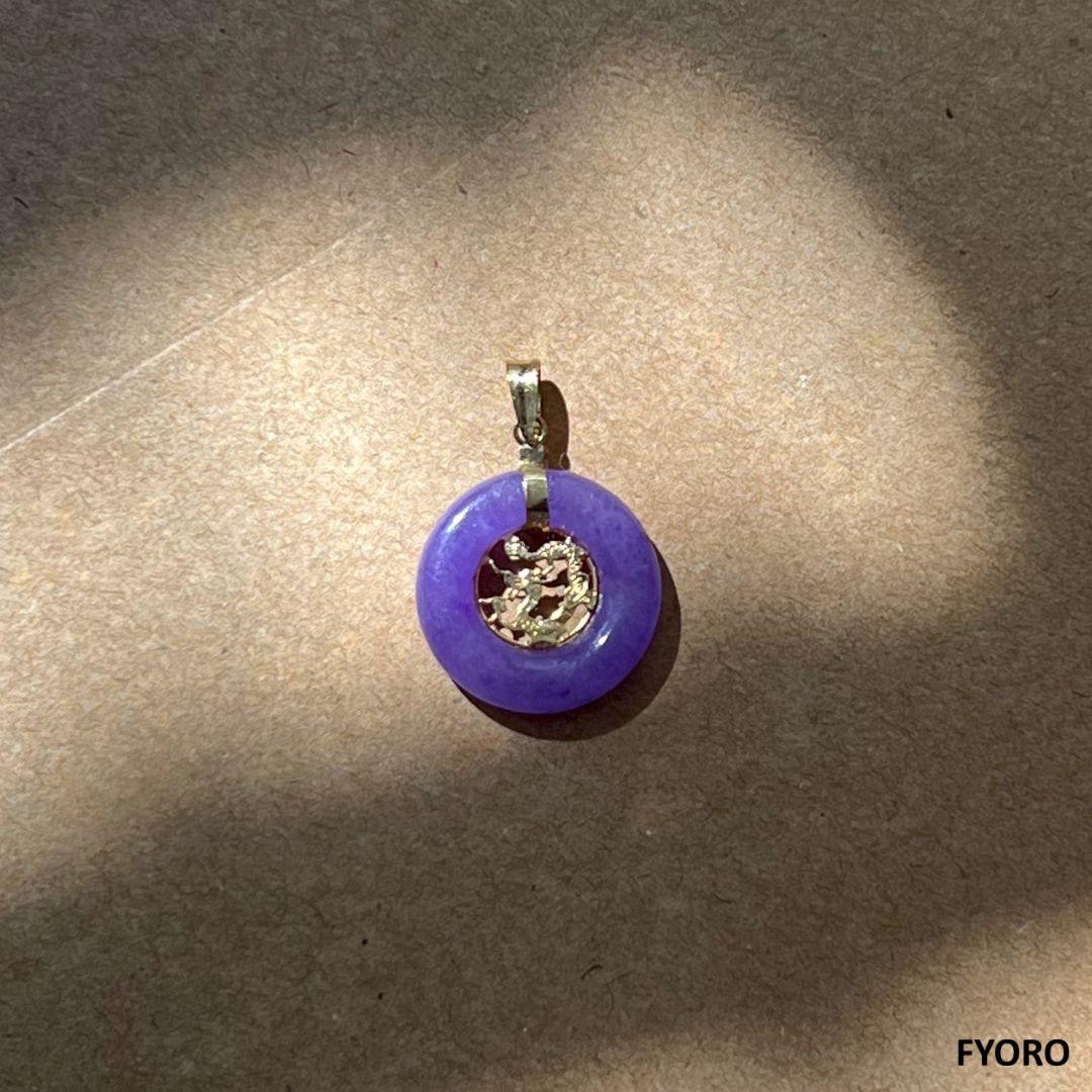 The 'Lantau Zhong Purple Jade Dragon Pendant is the medium sized version of our famous Lantau Jade Dragon Design. We have a donut of Purple Jade with our renowned dragon design cared in 14K Yellow gold in the middle. The interplay of optics creates