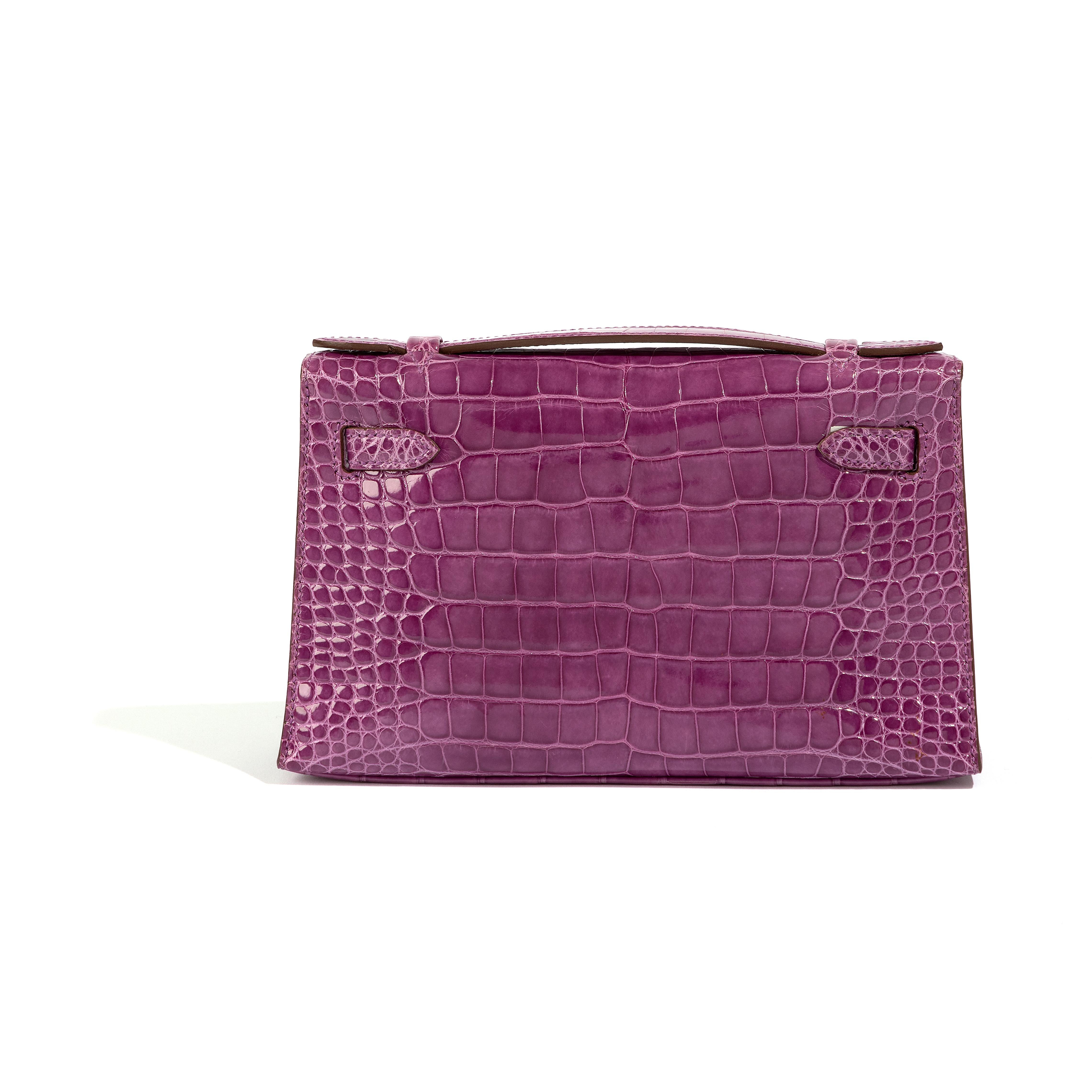 Inspired by Hermès' Kelly tote bag, designed with the iconic details of it's big sister and meticulously crafted from Crocodile skin Purple matte, this miniature Hermès Kelly Pochette clutch bag is sure to make a statement. Compact-sized, the piece