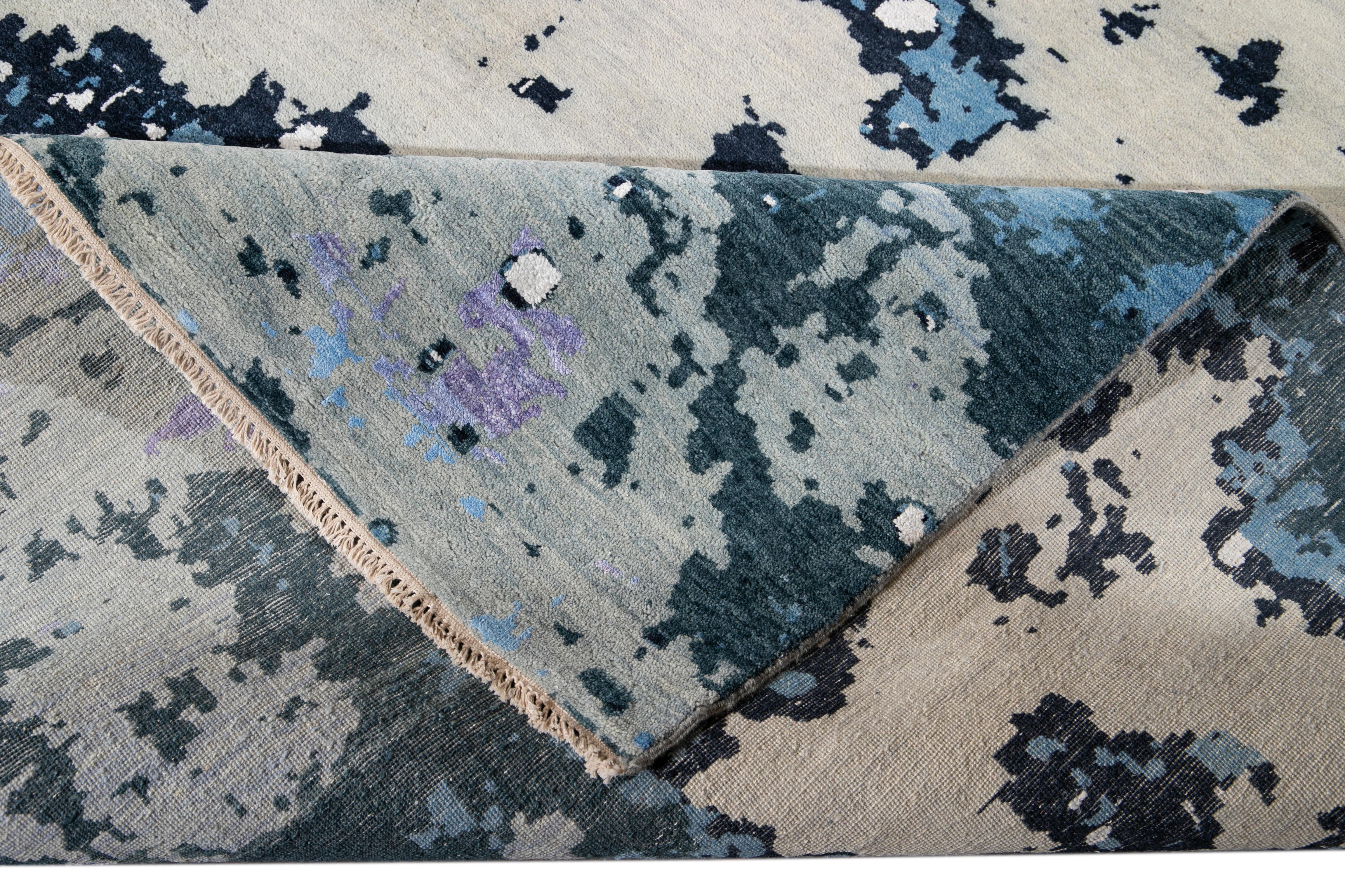 Bellissimo tappeto contemporaneo realizzato a mano in lana e seta con campo viola. Questo tappeto presenta accenti di blu, grigio e avorio in uno splendido disegno astratto all-over.

Questo tappeto misura: 12'2