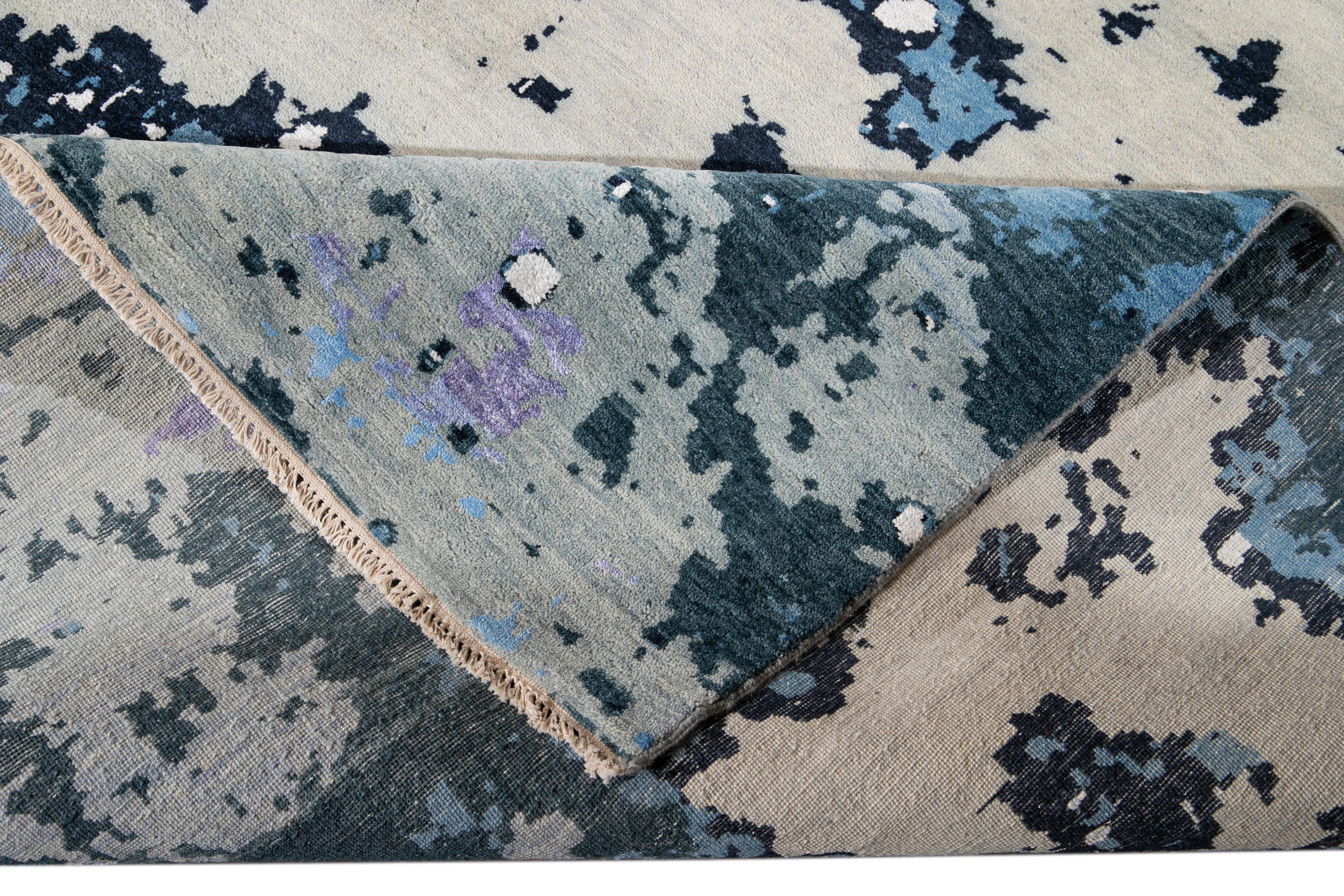 Beautiful contemporary Hand-made wool and silk rug with a purple field. This rug has accents of blue, gray, and ivory in a gorgeous all-over abstract design.

This rug measures: 12'2