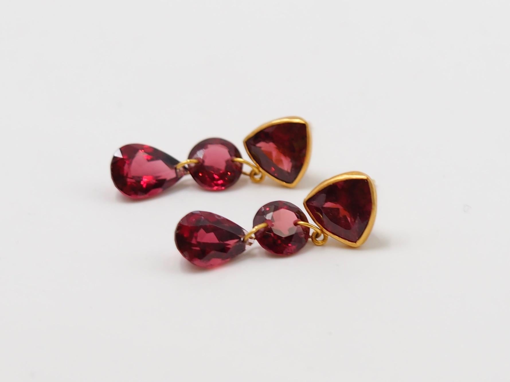 These earrings are composed of 6 purple / red garnets for a total weight of 16.7carats. 
The top part of the earrings presents a trillion shape garnet set in 22 karat gold linked to a round shape garnet (simple drilled) which leads to a pear shape