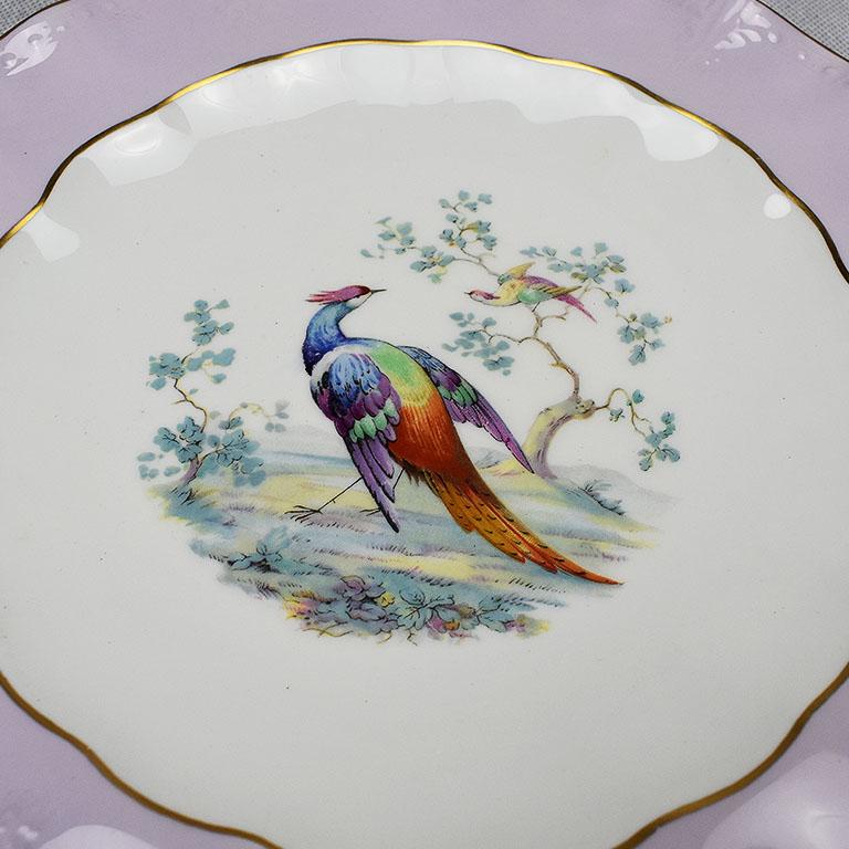 Royal Crown Derby bone china plate in purple with colorful peacock at center. This piece was created in the 1950s and features pale purple scalloped sides with double gold hand painted edges. At the center, a peacock in a rainbow of colors sits upon