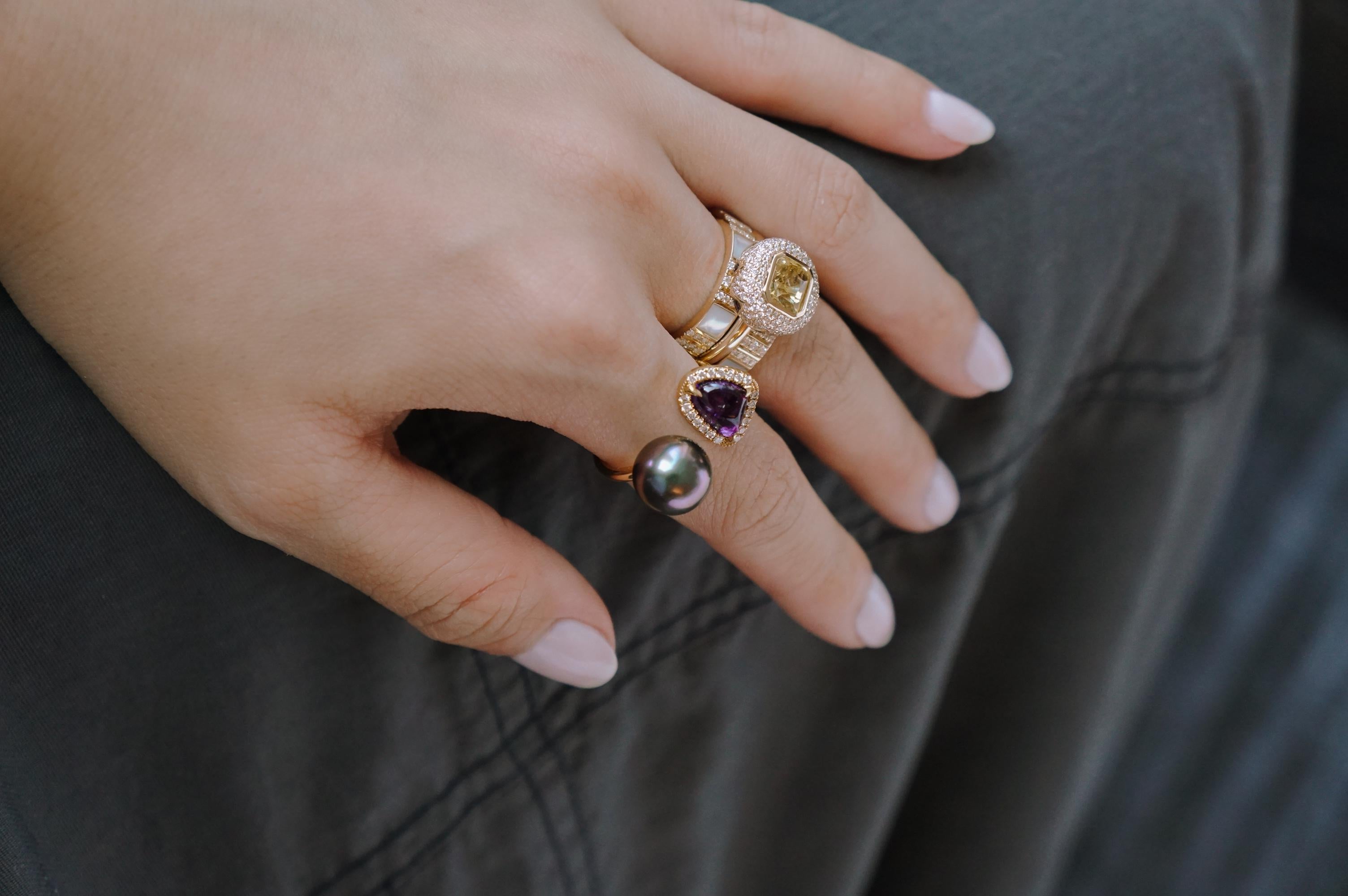 A contrast of a soft, organic form and a minimal, geometric sphere makes Ri Noor's Purple Sapphire and Tahitian Pearl and Diamond Ring a bold statement-making cocktail ring. The 18k yellow gold band wraps around the wearer's finger, presenting on