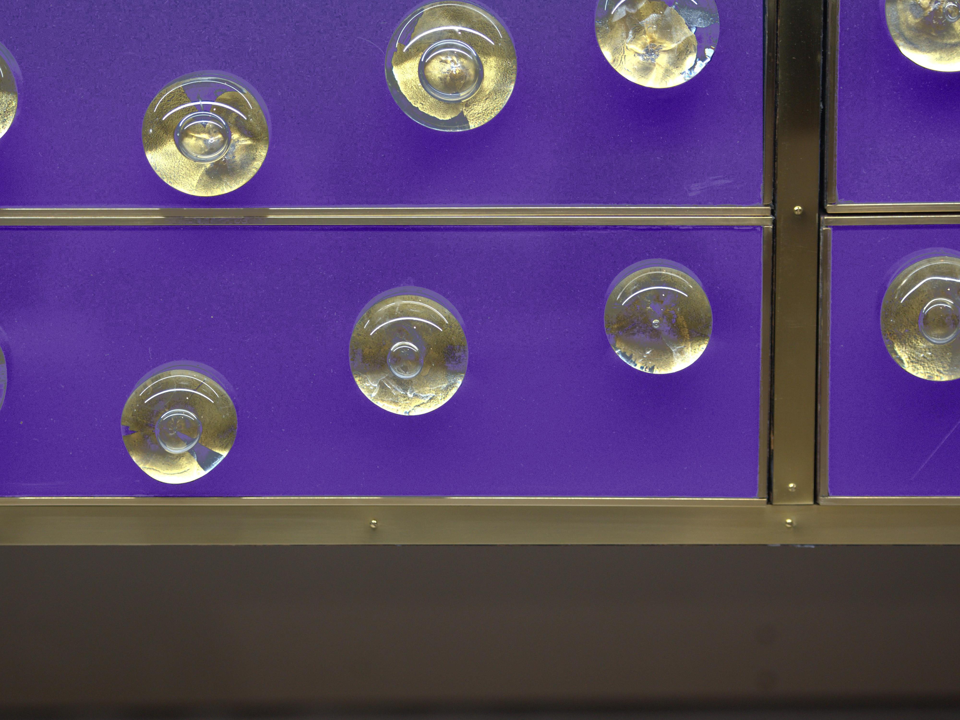 Dieses exquisite violette Sideboard mit Muranoglas ist ein hervorragendes Beispiel für italienische Handwerkskunst. 

Er ist aus massivem Birkenholz gefertigt, hat eine elegante Messingverzierung und ist mit 28 goldenen, kugelförmigen Juwelen aus