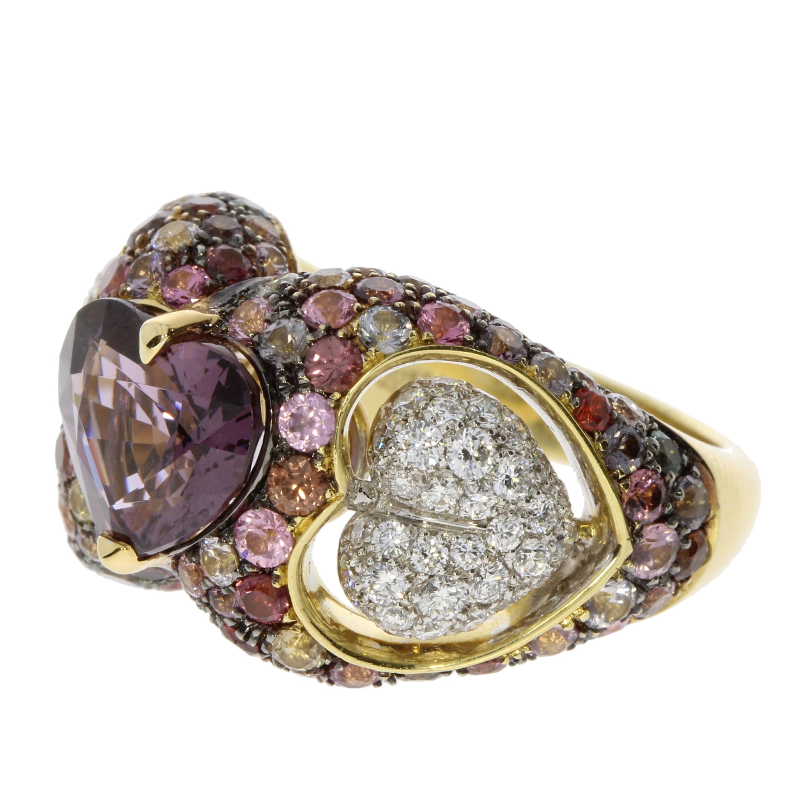 A vivid and intriguing Heart shaped Purple Spinel seats between of two suspended hearts of round brilliant cut White Diamonds. The ring is completed by a glittering pave of mixed-colour Spinels.
This ring is an original new engagement ring but is