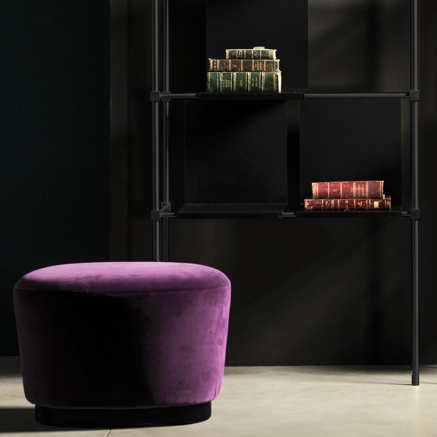 The Purple Spot Pouffe exudes a modern elegance with its clean lines and sleek silhouette. Distinguished by a solid wood base with a rich walnut finish, this pouffe is upholstered in luxurious purple velvet for a warm, moody feel. A luxurious yet