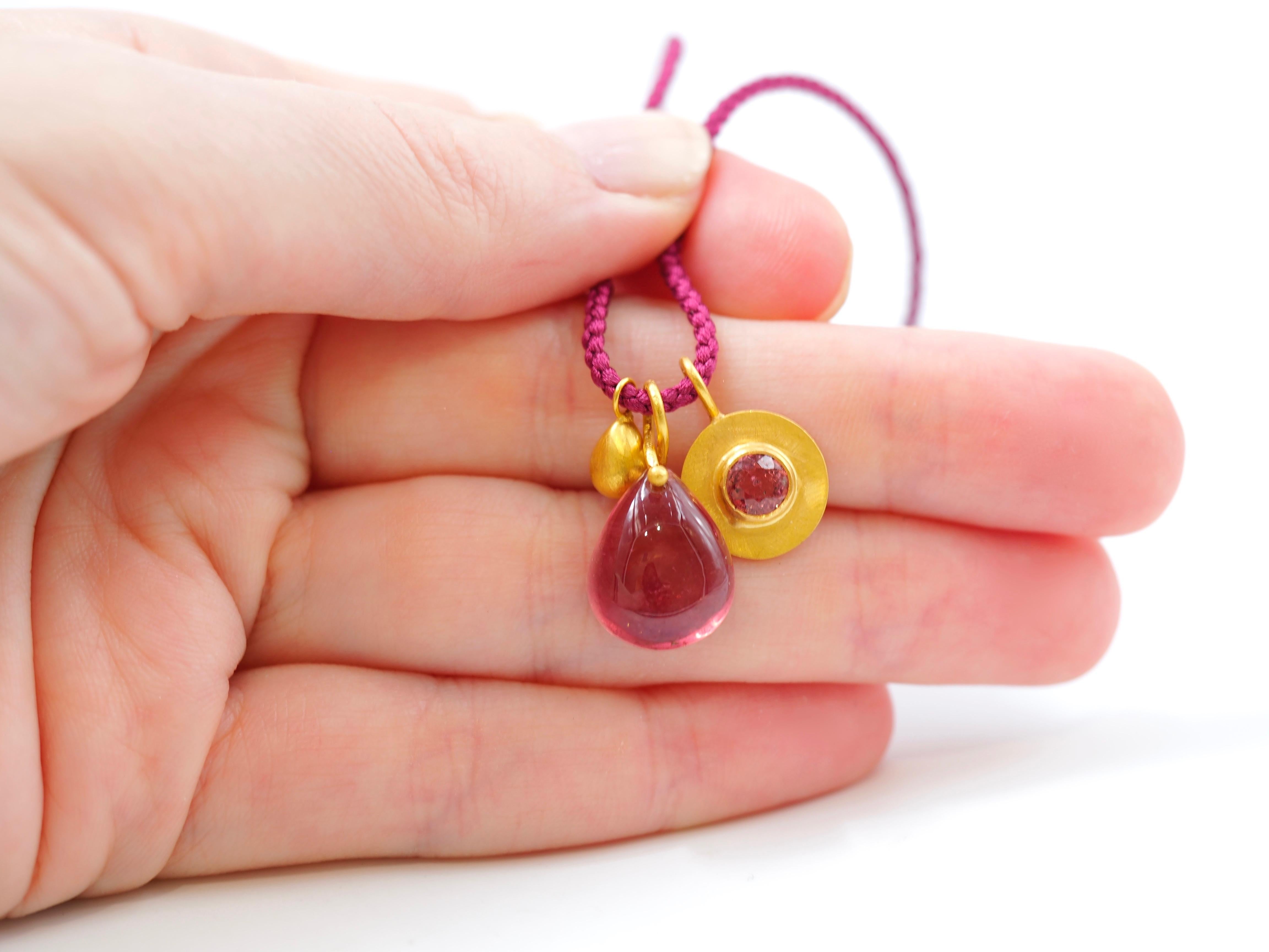 This necklace is composed of 3 pendants on a long braided silk rope:
- a large purple tourmaline drop cabochon of 10.35 cts
- a medium gold 22kt drop
- a gold disk with a purple spinel of approx 1 carat (12mm diameter)

A 22cts gold chain can also