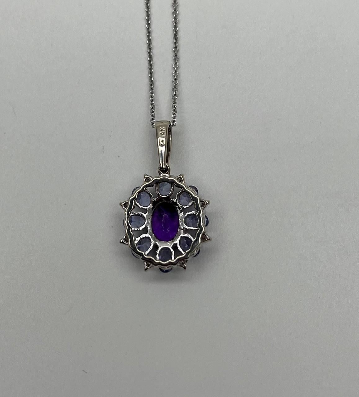 This exquisite piece features a central oval amethyst surrounded by a halo of smaller round diamonds and blue sapphires, all set in a lustrous metal.
The pendant's design is a harmonious blend of symmetry and sparkle, with each stone meticulously