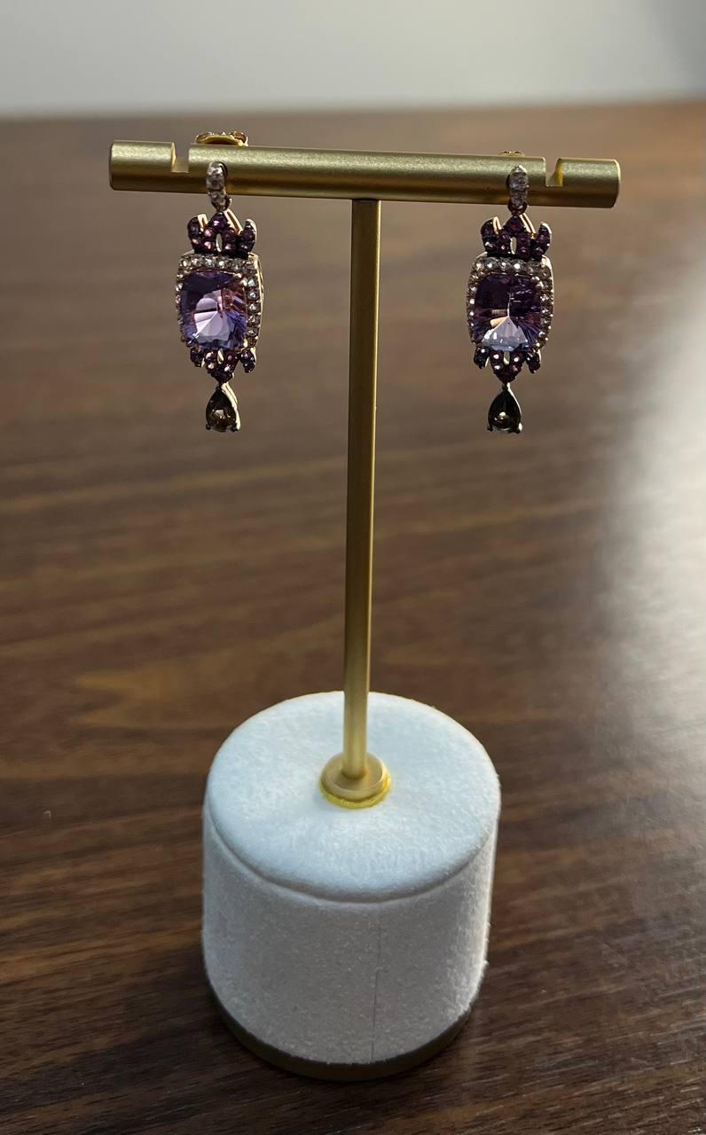 Eleganti orecchini pendenti e a goccia. Questi sofisticati orecchini presentano un'ametista centrale, sapientemente tagliata e sfaccettata per catturare la luce. Ogni pietra è circondata da un'aureola di piccoli diamanti scintillanti che esaltano la
