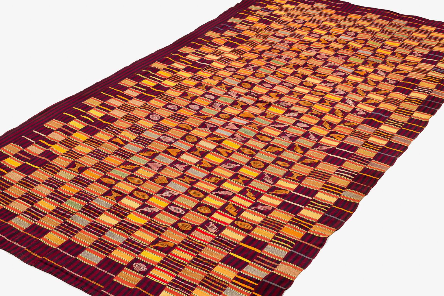Ce tissu Ewe Kenta pour homme est tissé dans des couleurs éclatantes : jaune citron, rouge, vert citron, vert foncé, orange et un peu de bleu sur un champ de bordeaux violet profond et d'indigo profond. Les motifs tissés représentent différentes