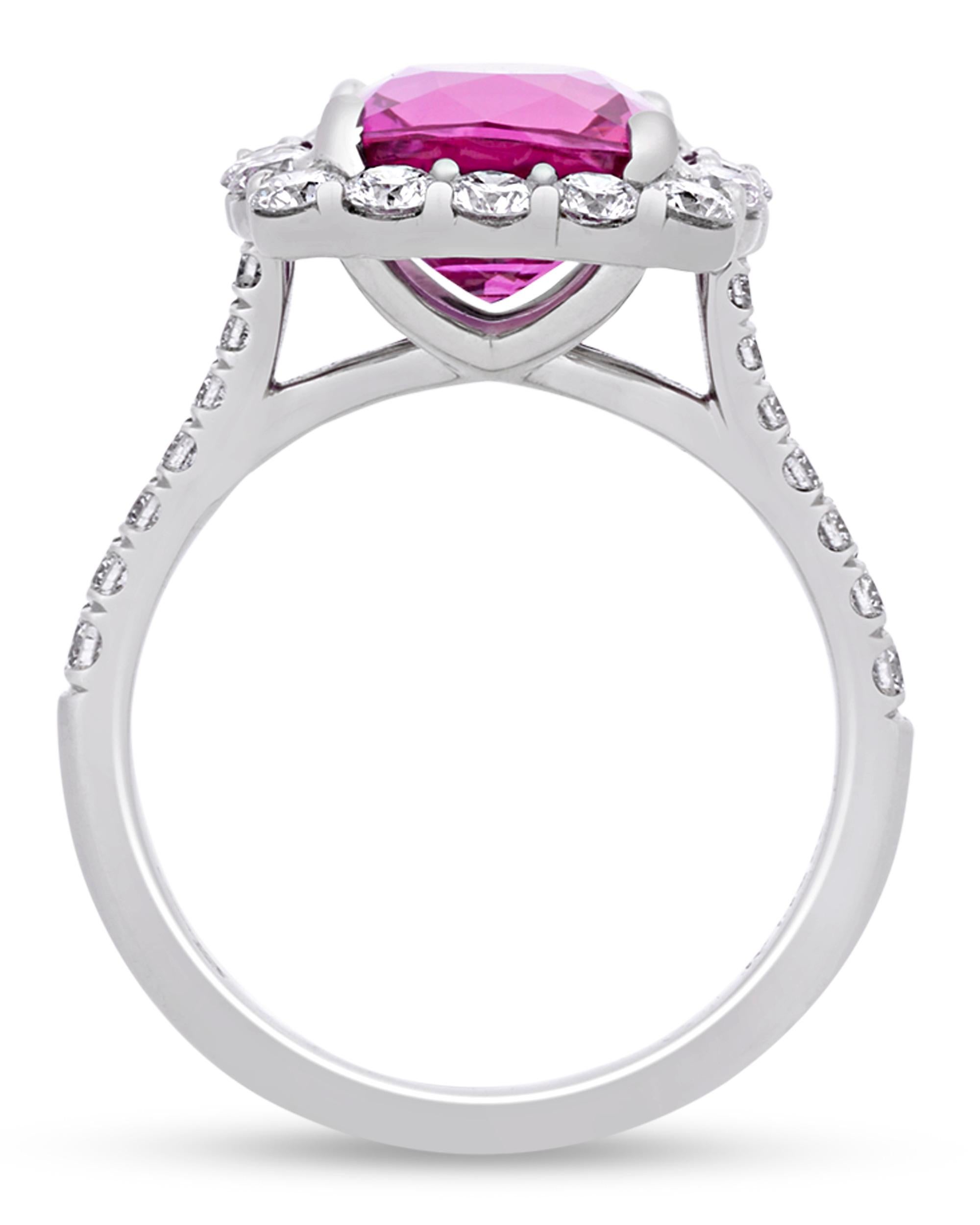 A striking cushion brilliant-cut purplish-pink sapphire, weighing 4.41 carats, sits at the center of this ring. The rosy jewel is encircled by round brilliant diamonds totaling 1.05 carats and set in platinum.
