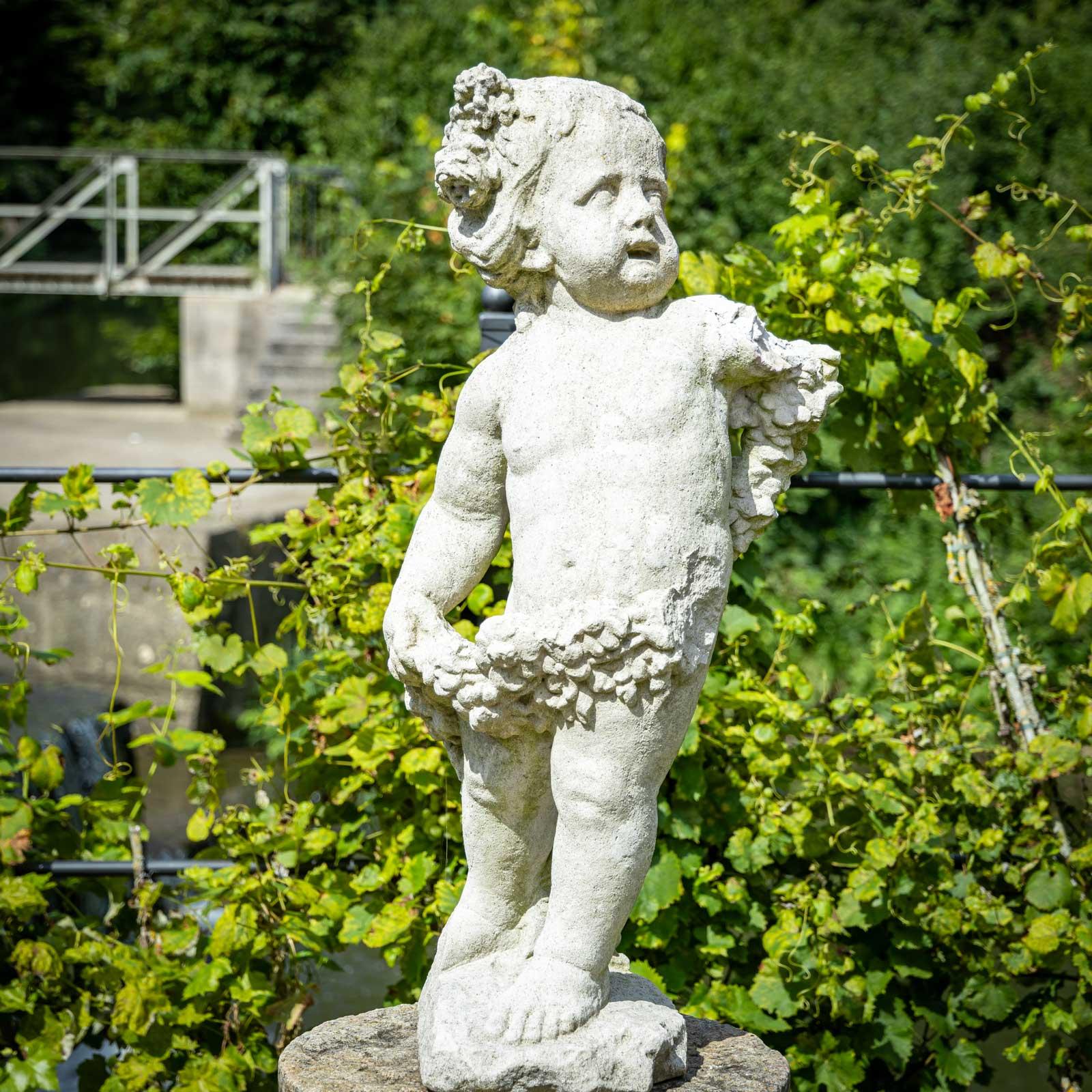 Figure de jardin en pierre moulée en forme de putto, personnification du printemps, vêtue d'une guirlande de fleurs et d'autres fleurs dans les cheveux.