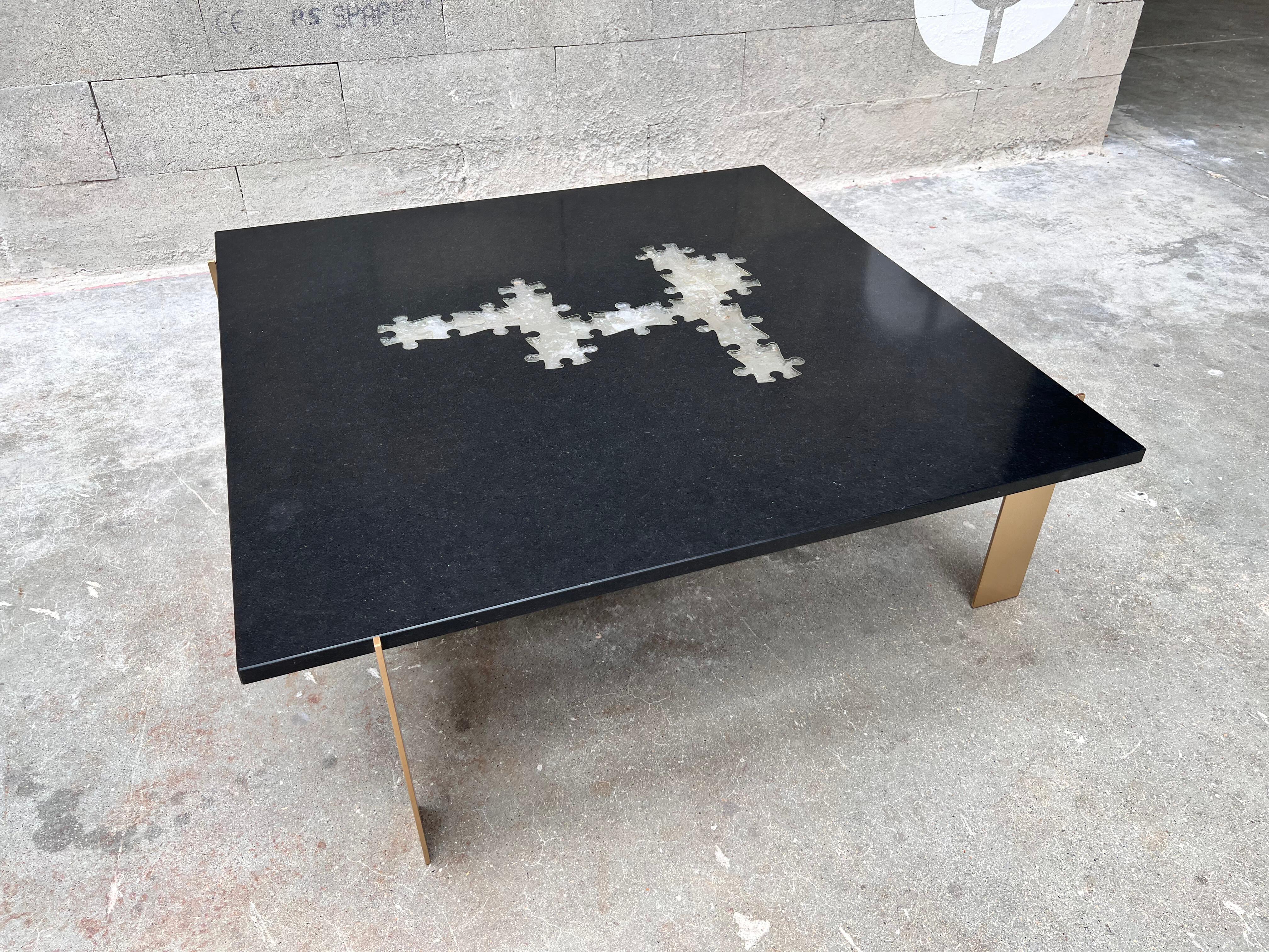 Large puzzle-shaped coffee table in black Zimbabwean granite and Madagascar rock crystal inclusions.  The base consists of 4 solid brushed brass supports arranged asymmetrically.

Zimbabwe black granite: often referred to as “Zimbabwe marble”, is a