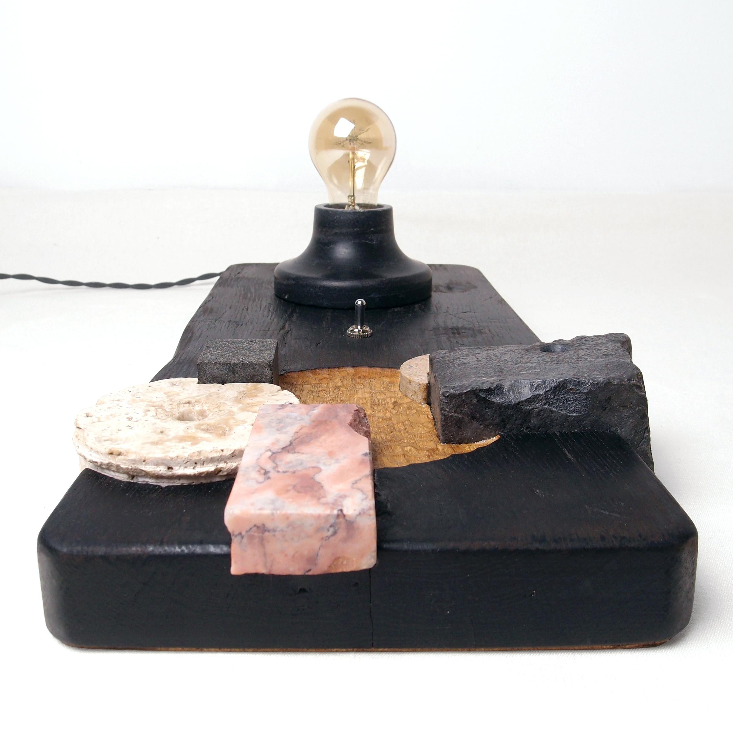 Puzzle Table Lamp by Gabor Gobi
Unique Piece.
Dimensions: D 24 x W 47 x H 11 cm.
Materials: Pine wood, beech wood, and limestone.

This meticulously crafted lighting piece is birthed from an artfully repurposed chopping board, residual stone
