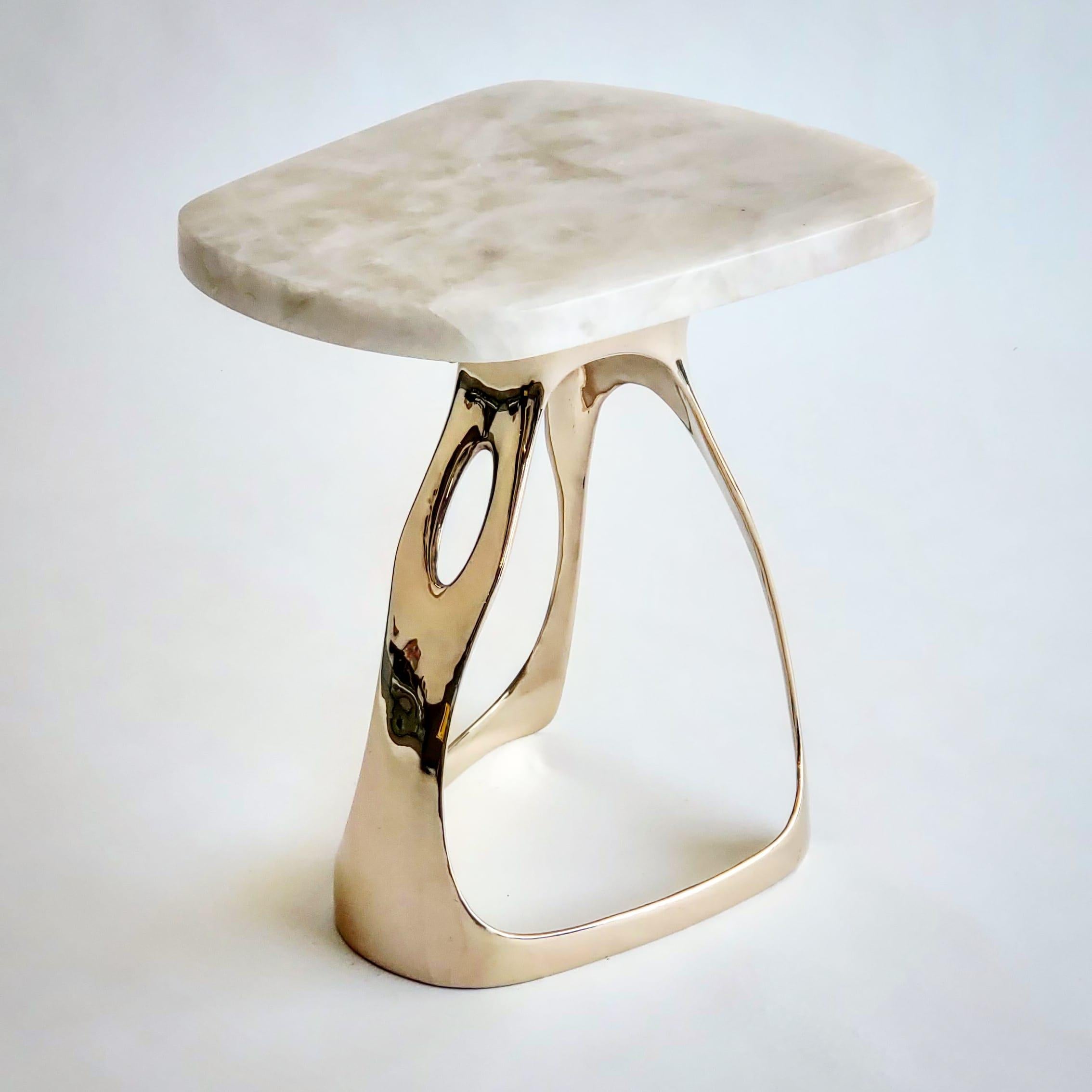 The Pyra drink table is a playfully organic piece of functional art. The piece is cast in bronze, hand polished and fitted with a prominent top cut from beautiful white quartzite stone. Materials - Bronze and white quartzite top.

Hand forged and