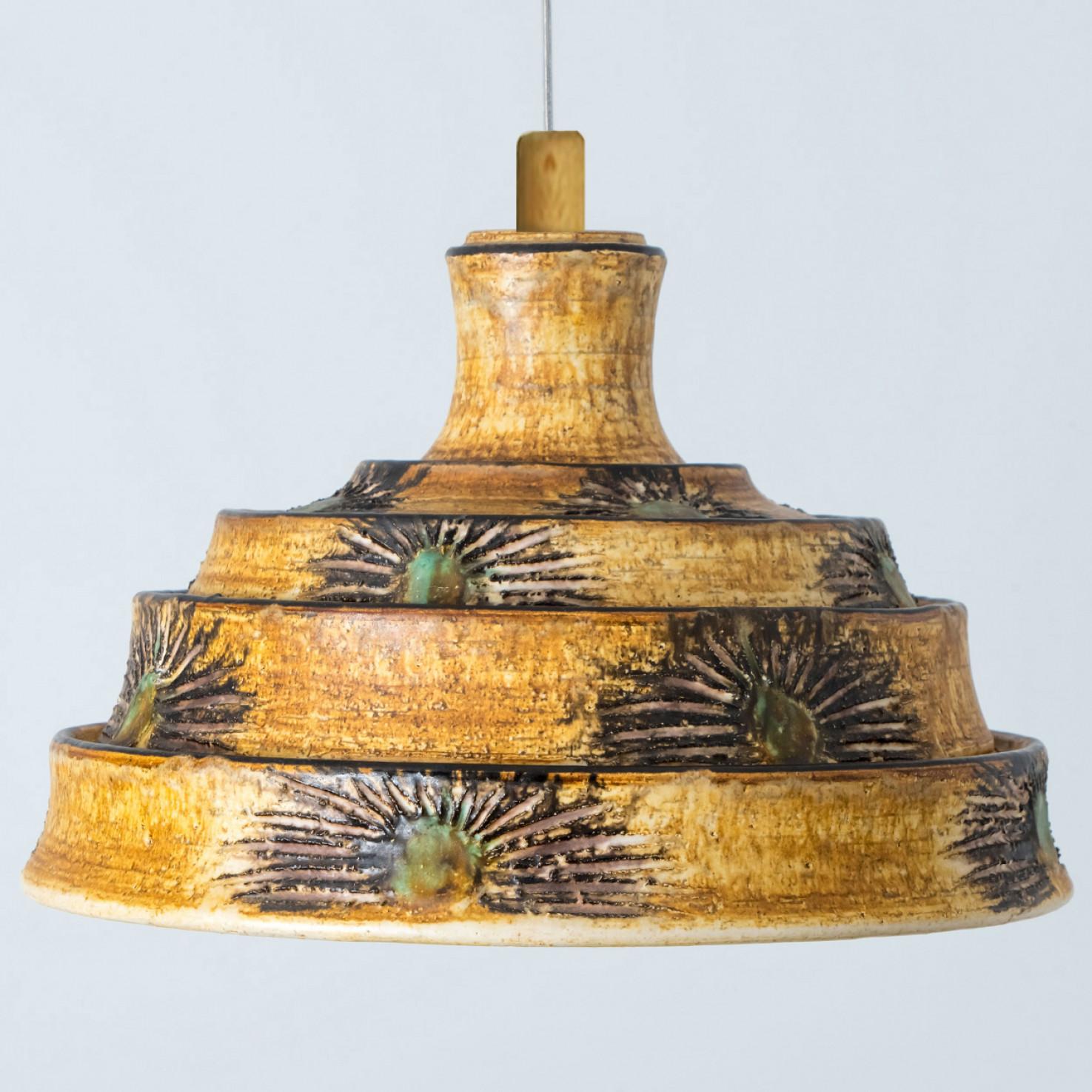 Superbe lampe suspendue ronde à la forme inhabituelle, fabriquée dans les années 1970 au Danemark avec des céramiques aux riches couleurs brunes et jaunes. Nous disposons également d'une multitude de jeux de lumière et d'arrangements uniques en