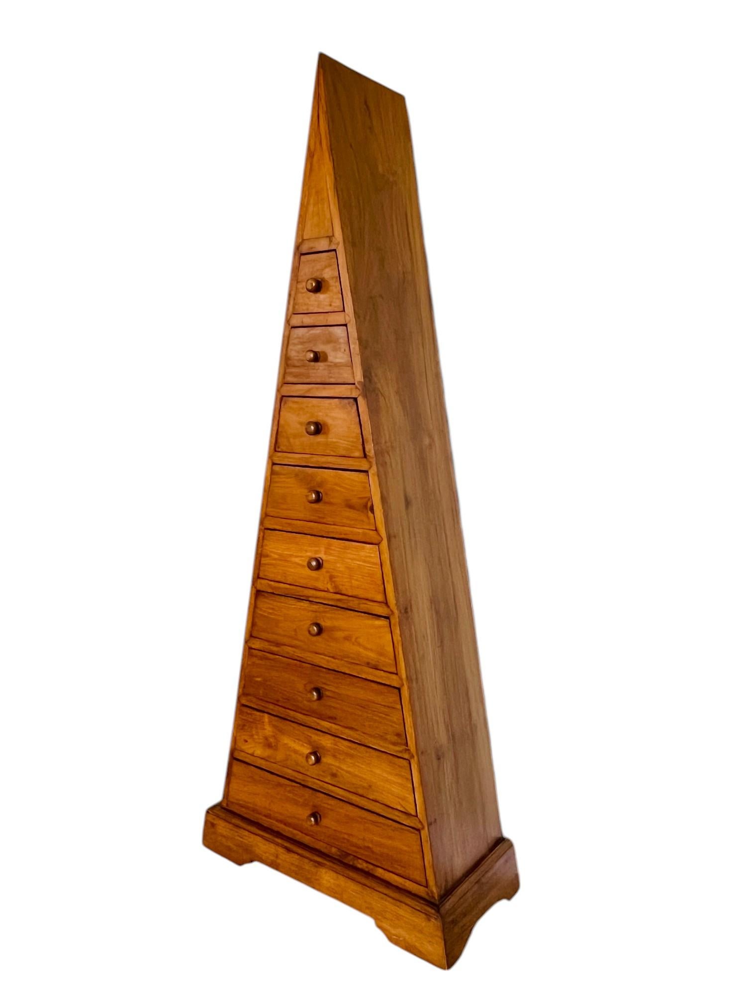 Una cassettiera contemporanea in legno duro a forma di piramide. Interessante design triangolare con struttura ad A e nove cassetti graduati con pomelli rotondi. Costruito in robusto legno massiccio con bellissime venature e tinto in finitura noce