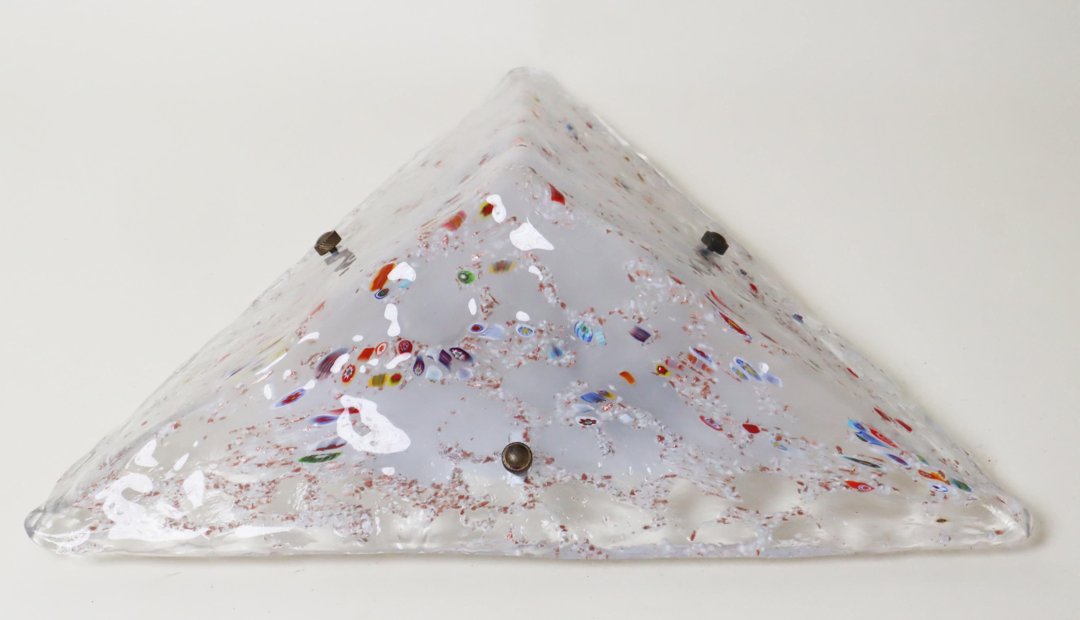 Diese atemberaubende Lampe in Form einer dreibeinigen Pyramide wird Sie mit ihrem einzigartigen und seltenen Murano-Glas begeistern. Das Glas ist mit zahlreichen kleinen Mustern verziert, die aus Glasstäben herausgearbeitet und in das klare Glas