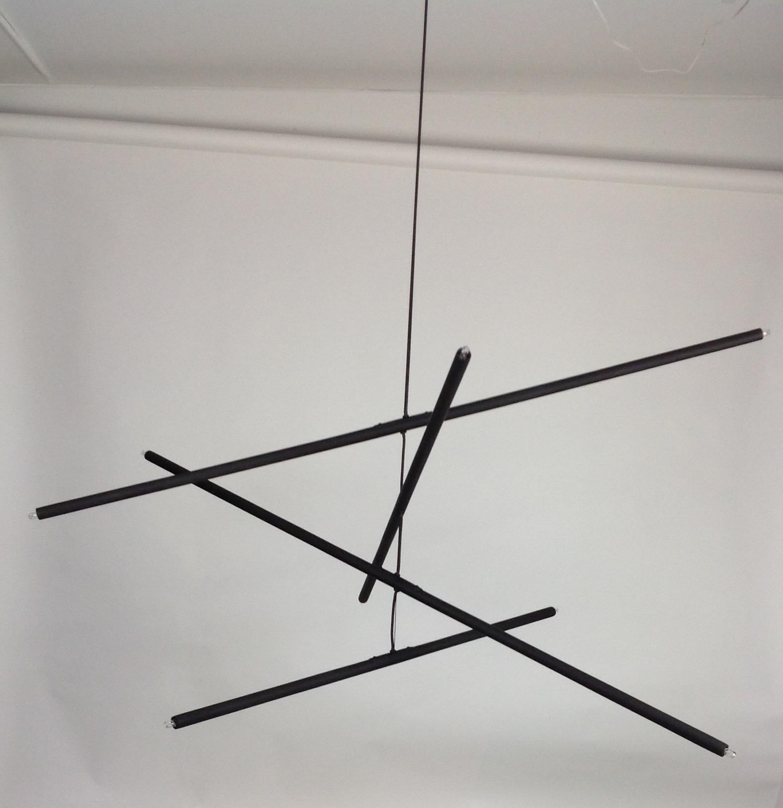 Mobil, come un mobile scultoreo, questo lampadario bilancia l'artigianato raffinato con una sobria eleganza. Le aste in gesso rifinite a mano, ognuna delle quali ospita una presa alogena, sono delicatamente sospese a un filo d'acciaio di seta, che