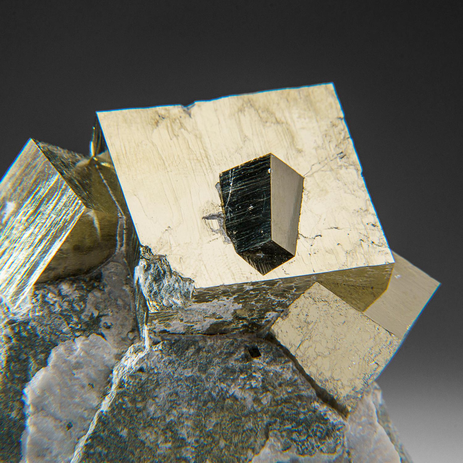 Three large cubic pyrite crystals with intergrown smaller pyrite crystals perched on Basalt matrix. The pyrite crystals have smooth faces and sharp edges, stands upright nicely without additional support. A must-have for any collection, these unique