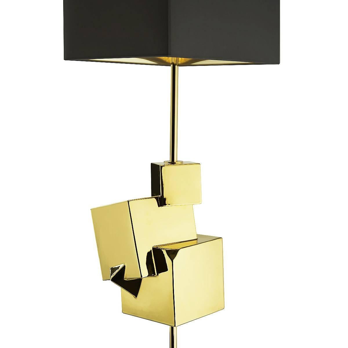 Made of metal and ceramics, this striking floor lamp will make a statement in a contemporary living room, thanks to its warm gold color and the decorations that adorn its structure in the shape of cubes of different sizes that create a dynamic