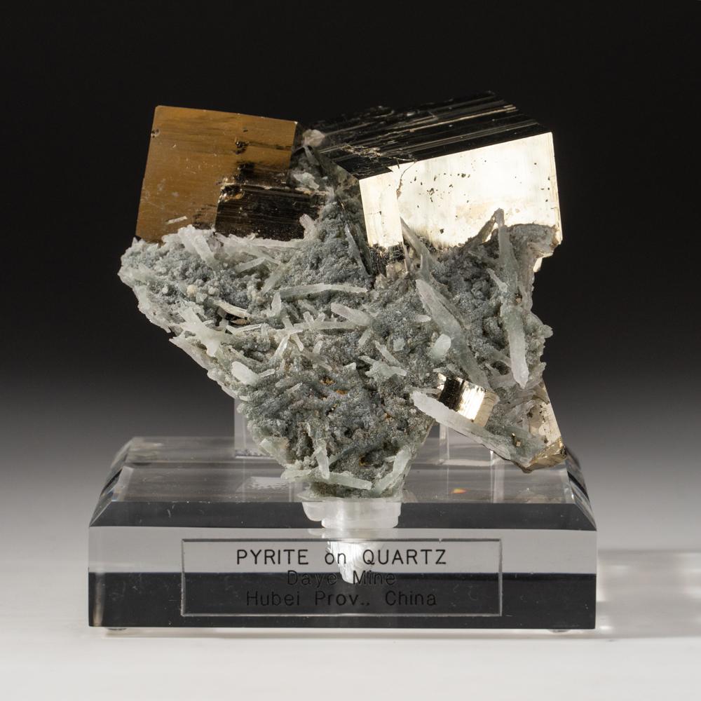 From Daye Mine, Hubei Province, China.

Large metallic mirror luster intergrown cubes of golden pyrite on quartz and pyrite enriched matrix lined with tabular translucent quartz crystals. Custom acrylic display stand included.

388 grams,