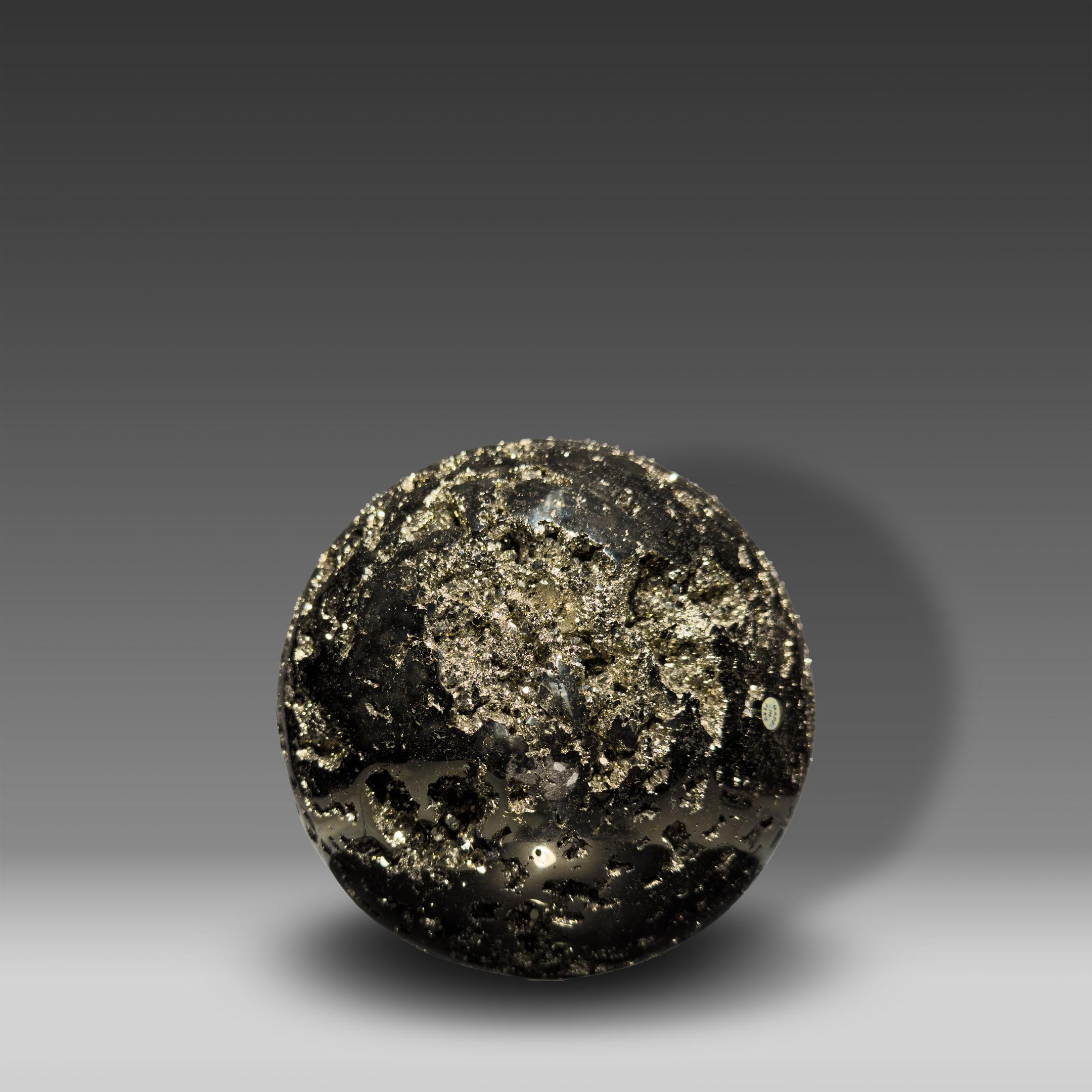 This striking Pyrite sphere from Peru is a dramatic decorative object with a presence. Measuring 7.5 inches in diameter and weighing nearly 30 pounds, it blends natural wonder with sculptural elegance. Its polished surface gleams with a mirror-like