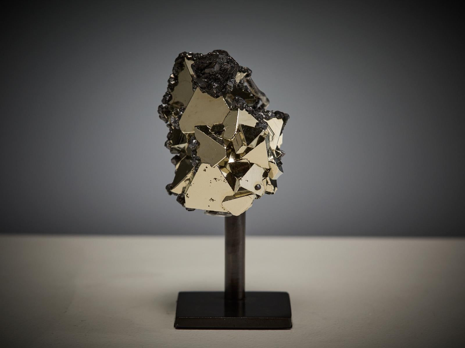 A beautiful specimen of pyrite with hematite from Peru, composed of sharp triangular crystals with perfectly smooth faces and a brilliant metallic lustre. The bright golden surfaces contrast beautifully with the black hematite, enhancing the