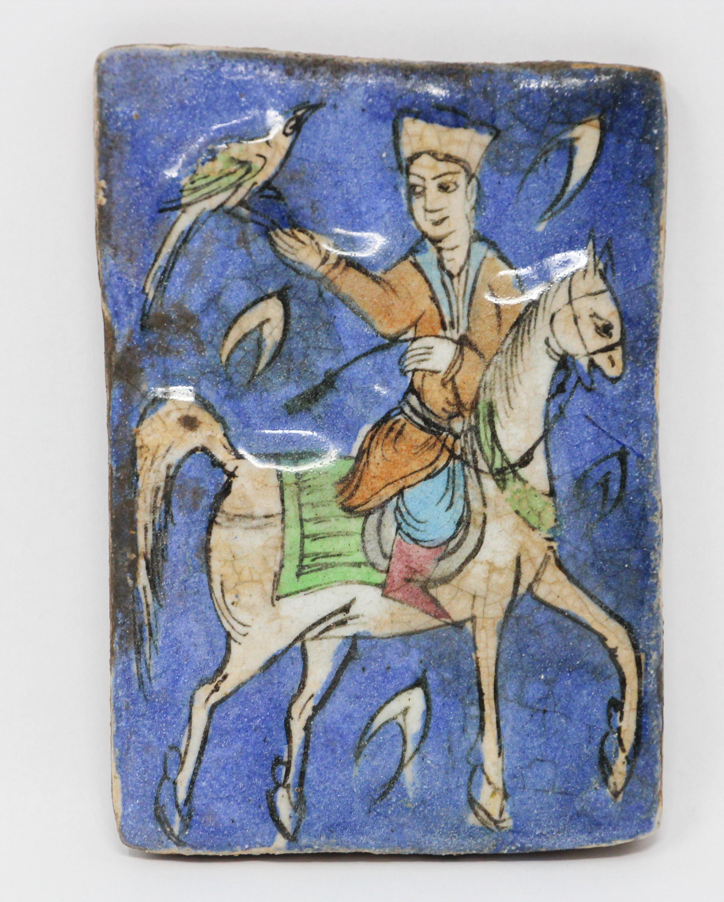 Beautiful Turkish ceramic blue glazed tile hand painted with a young man riding on horse holding a bird.
Qajar Middle Eastern style under-glazed pottery ceramic tile with raised hand painted design.
Handcrafted decorative crackle glazed ceramic
