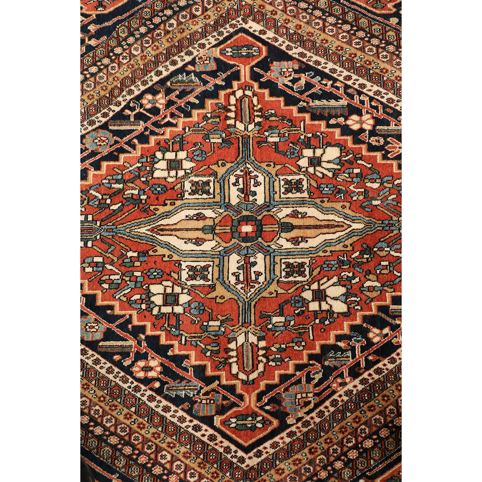 This Qashqai Persian carpet circa 1920 in pure wool and vegetable dyes features an overall rhombic garden design with multiple bands designating both the central field pattern and border. Organic red, light blue, green and gold colors are balanced