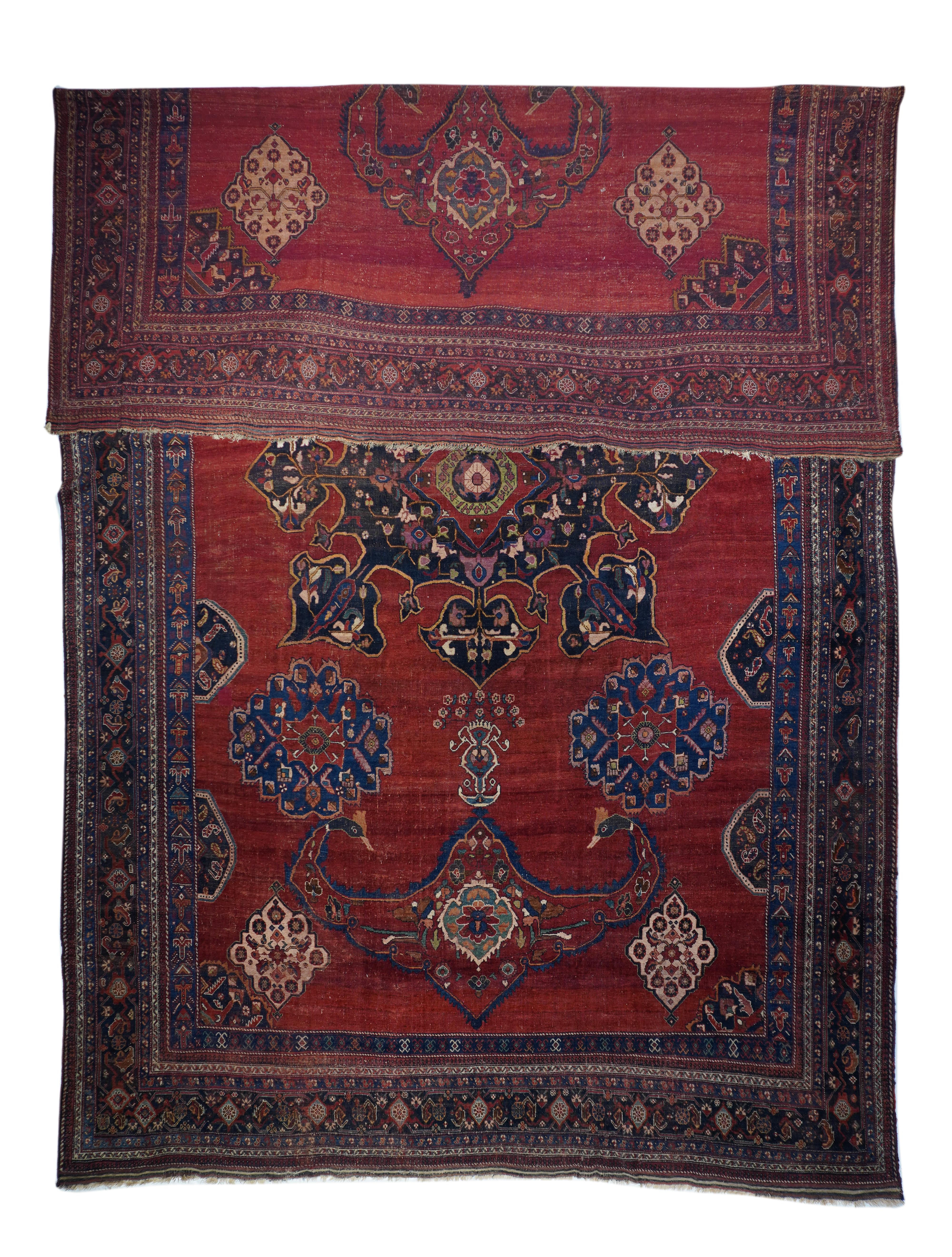 This is a rare SE Persian nomadic carpet in a large size, probably originally woven for a wealthy local patron. The nicely abrashed warm red madder field show an extravagantly developed navy-black medallion with eight spadiform pendants, vertically