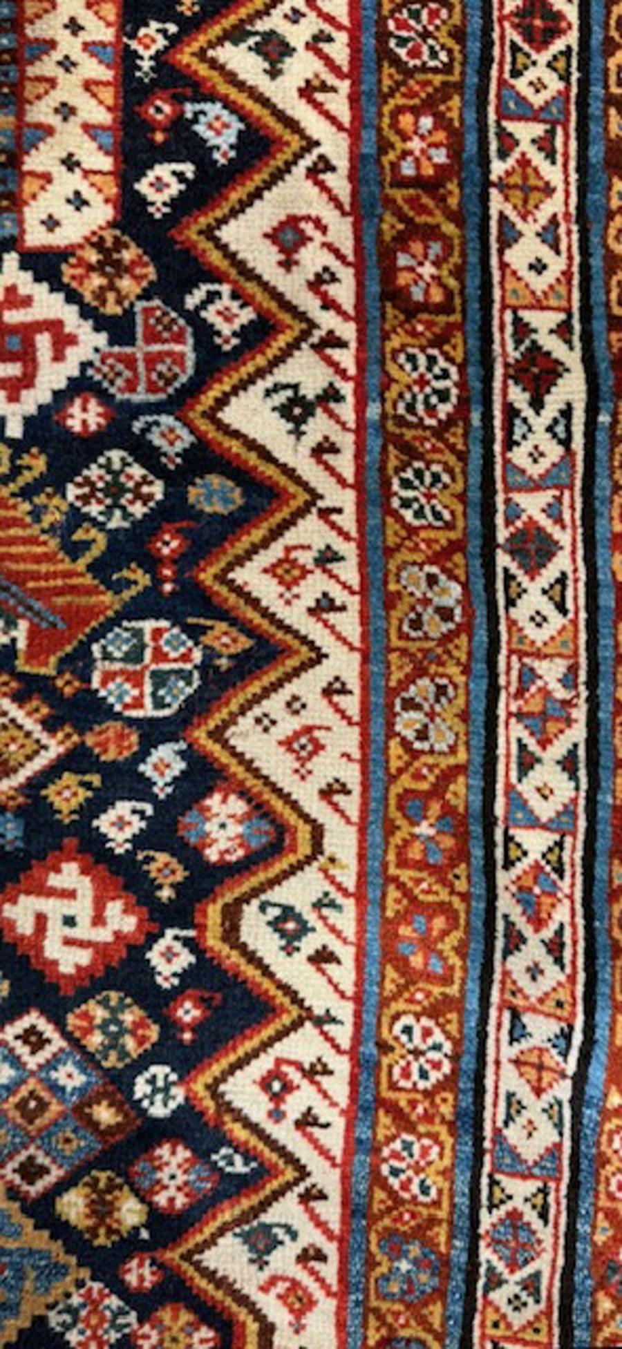 

Qashqai rug from south west Persia (Iran)

Age: circa 1885

Size: 6′.1″x3′.4″ (185×102 cm)

The navy subfield has lateral zigzags and encloses five polychrome mosaic diamonds,striated leaves,tiny botehs,pinwheels,palmettes,squares,triangles and